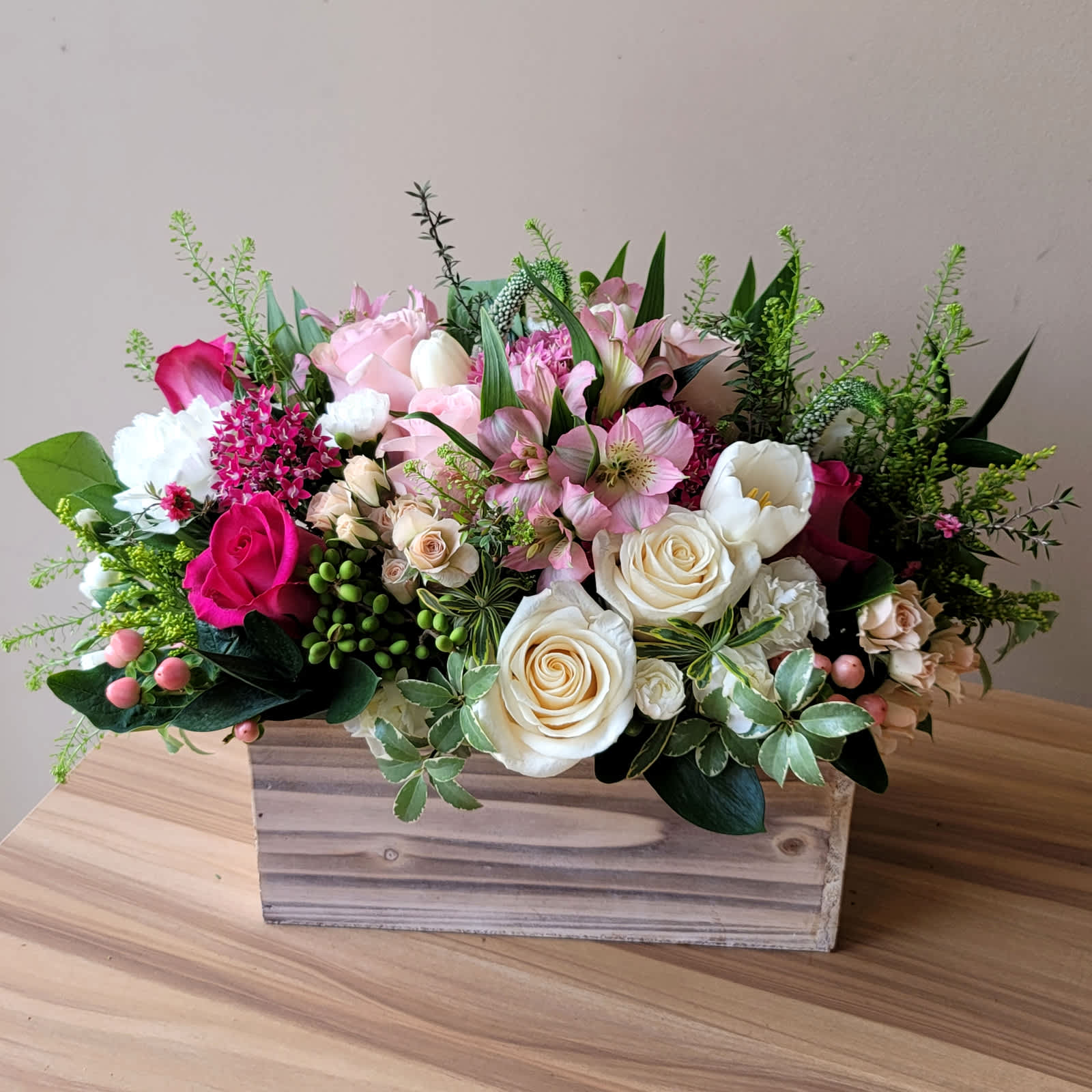 Mixed pink and white flowers arranged in a wooden box