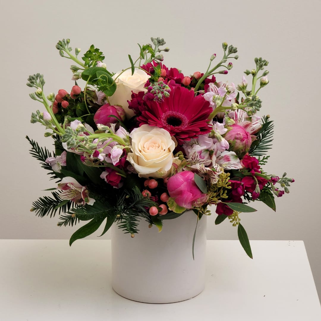 Pink and white floral arrangement in a white cylindrical vase