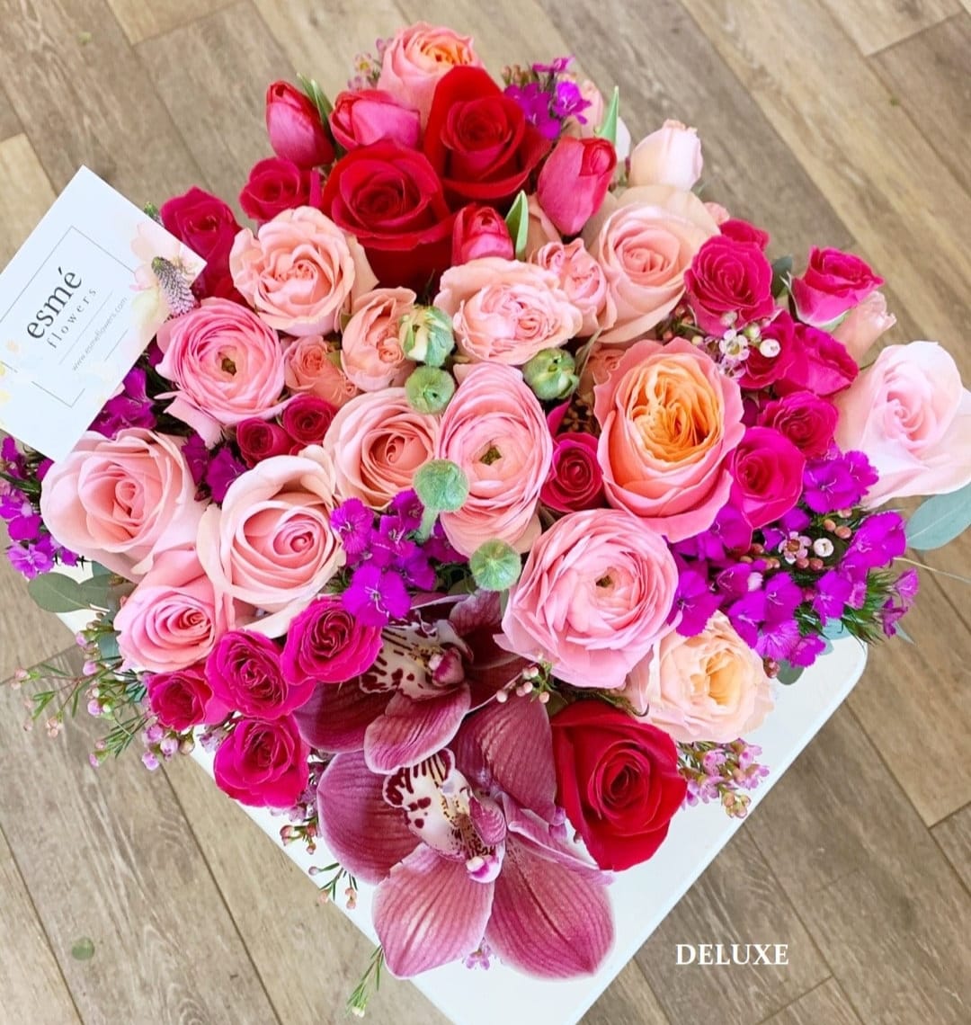 Bouquet of pink and red roses with purple orchids in a white box