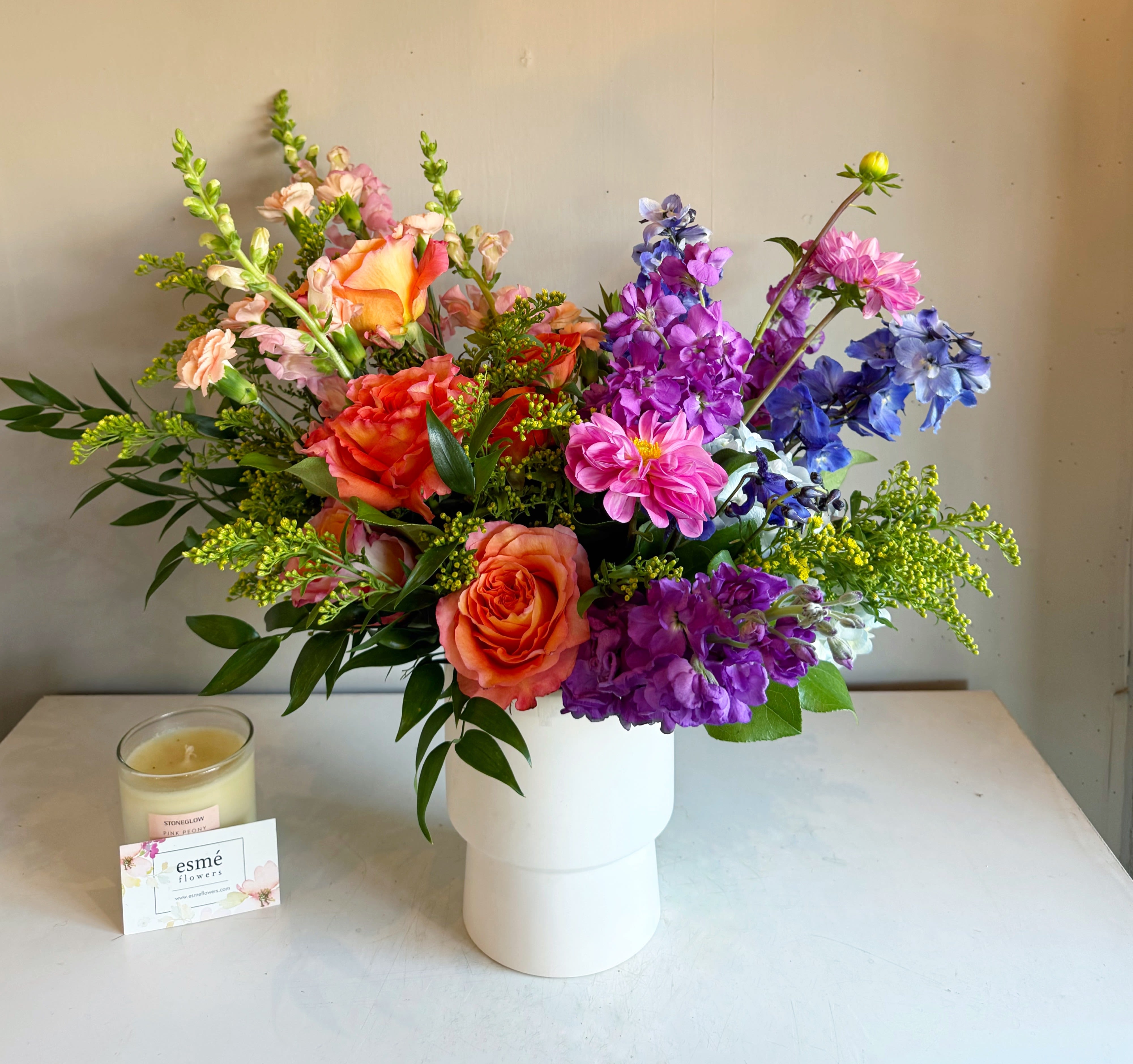 Colorful mixed bouquet in a white vase with pink, orange, purple, and blue flowers