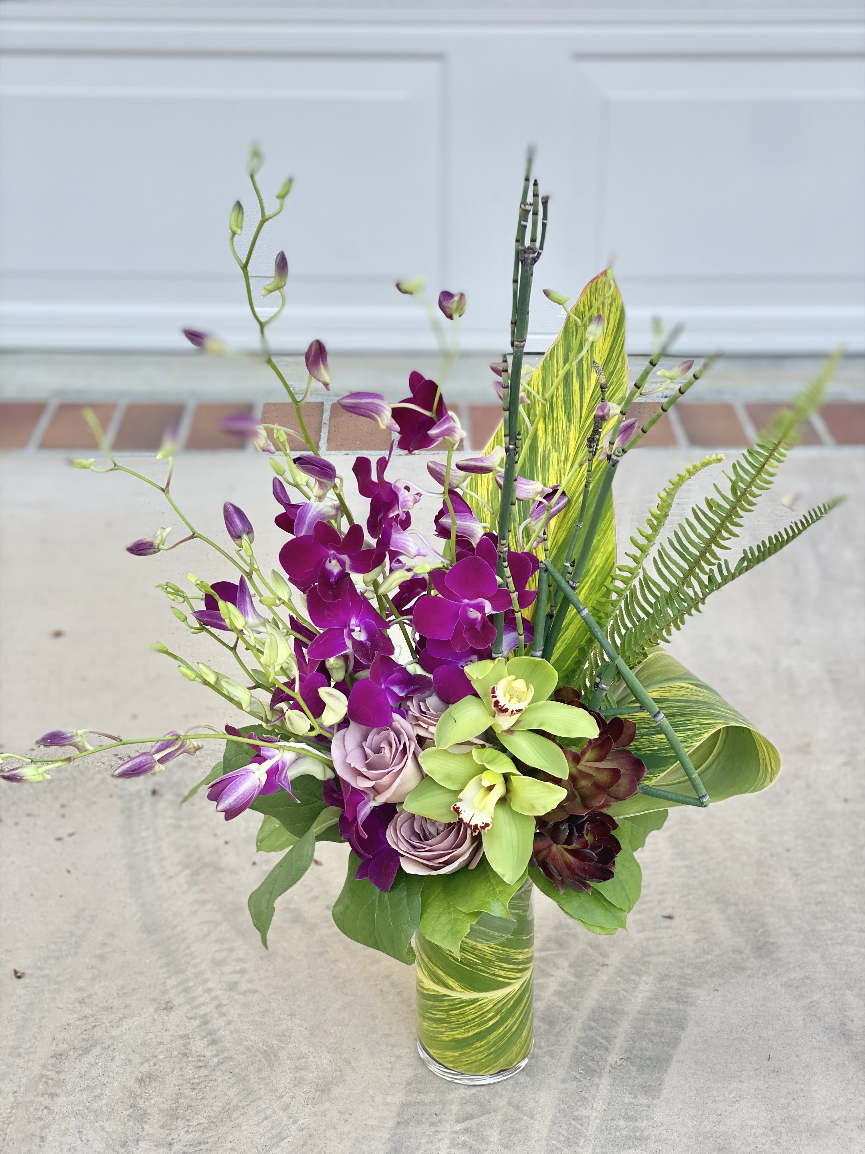 Orchid Dance - She looks even more gorgeous and vibrsnt in person! Intentional selection if hardy blooms, this includes: 2 types of orchids, roses, fun tropical foliage, and lots of artistic design flare!
