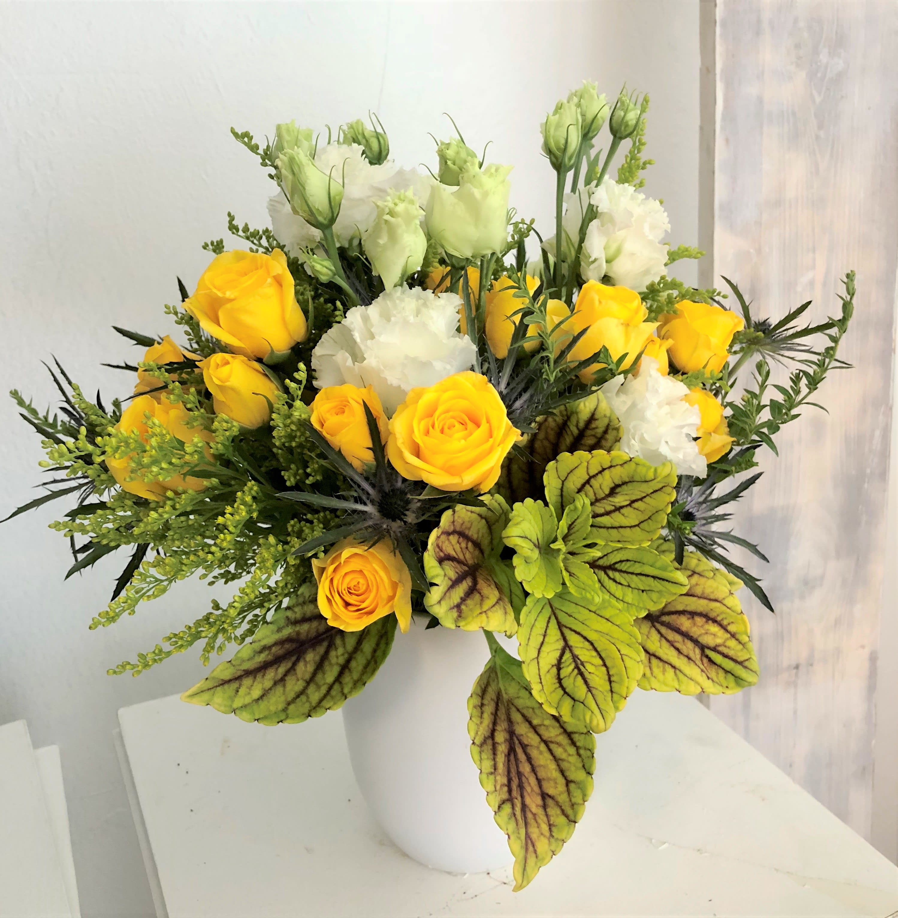Sunshine State of Mind - A combination of bright yellow and white seasonal flowers will be combined with a variety of textures. Made in white vase, with a sunny vibe. 