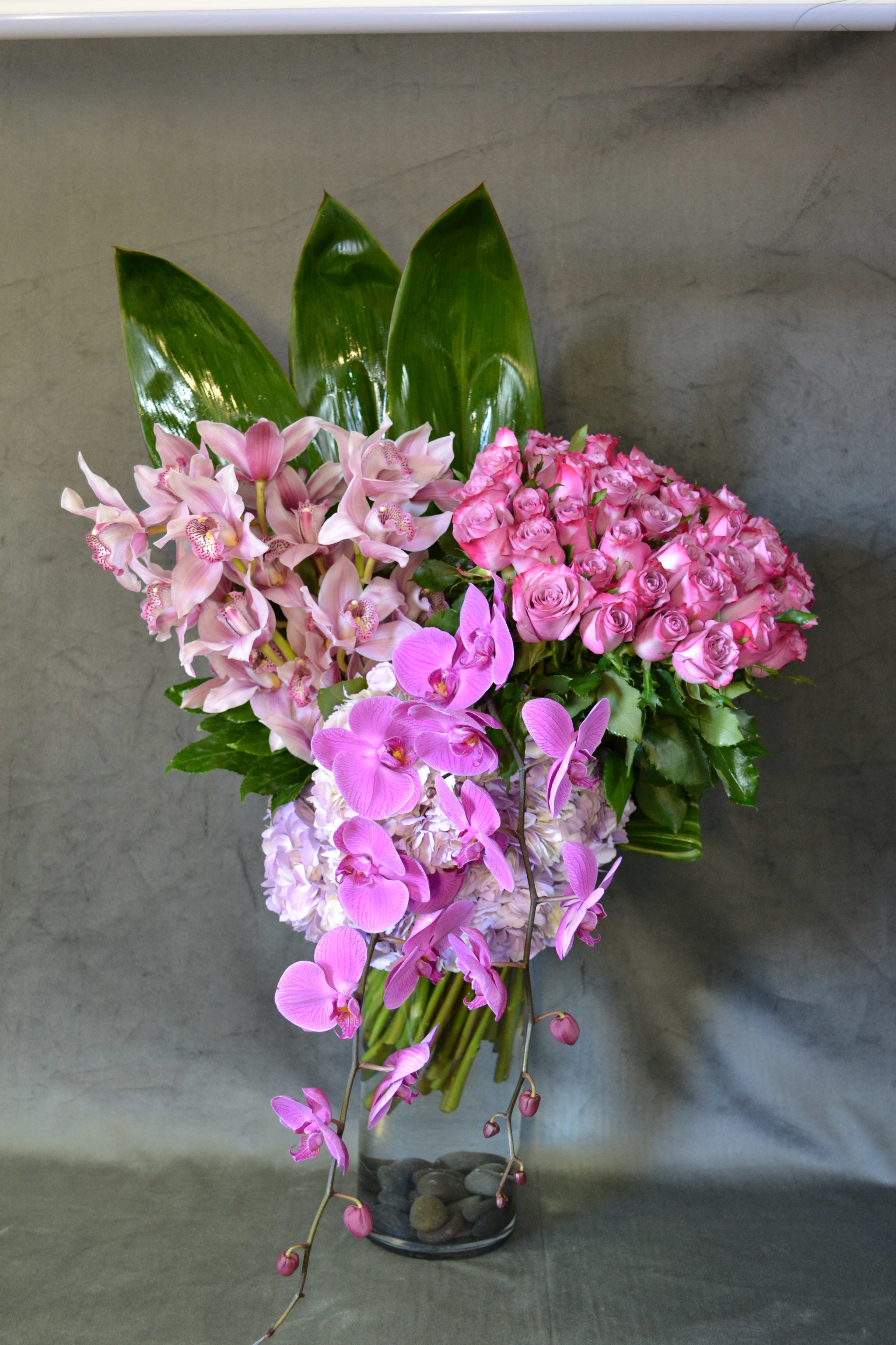 Destiny - Roses, Hydrangeas, Cymbidium Orchids, Phalaenopsis Orchids. Perfectly combine and arranged in a tall glass vase.