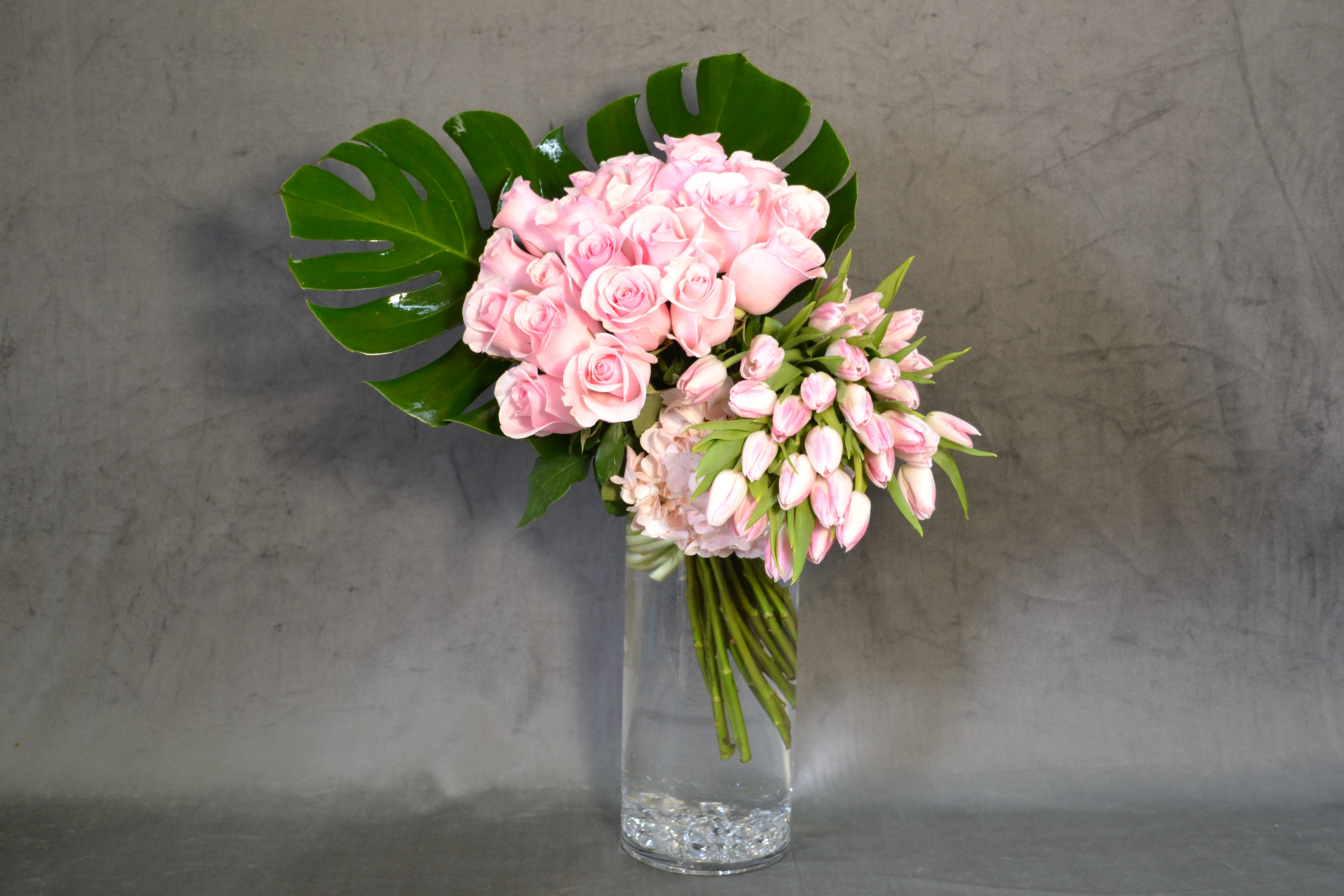 Sugar Baby - Cylinder tall vase holding long stem Pink Roses with exquisite Tulips.