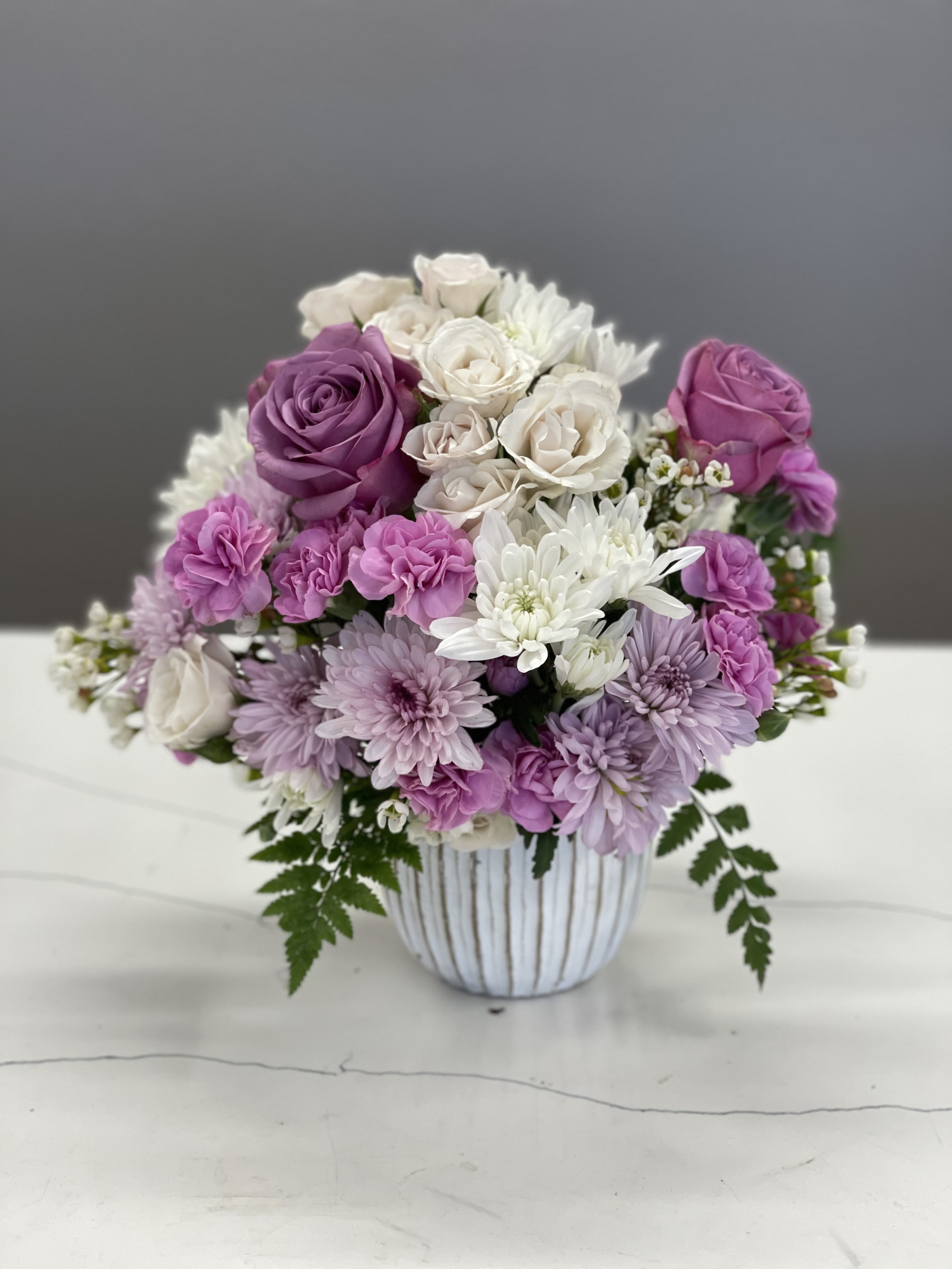 Bouquet of pink, purple, and white flowers in a striped vase