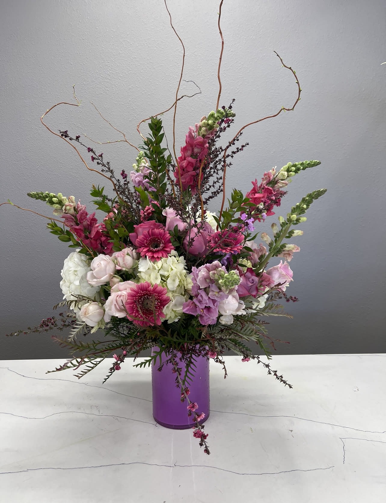 Pink and white floral arrangement in a purple vase