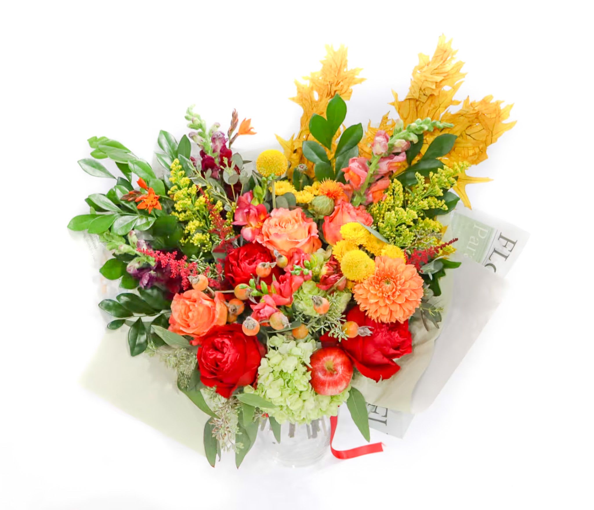 Mixed bouquet of red, orange, and yellow flowers in a clear vase