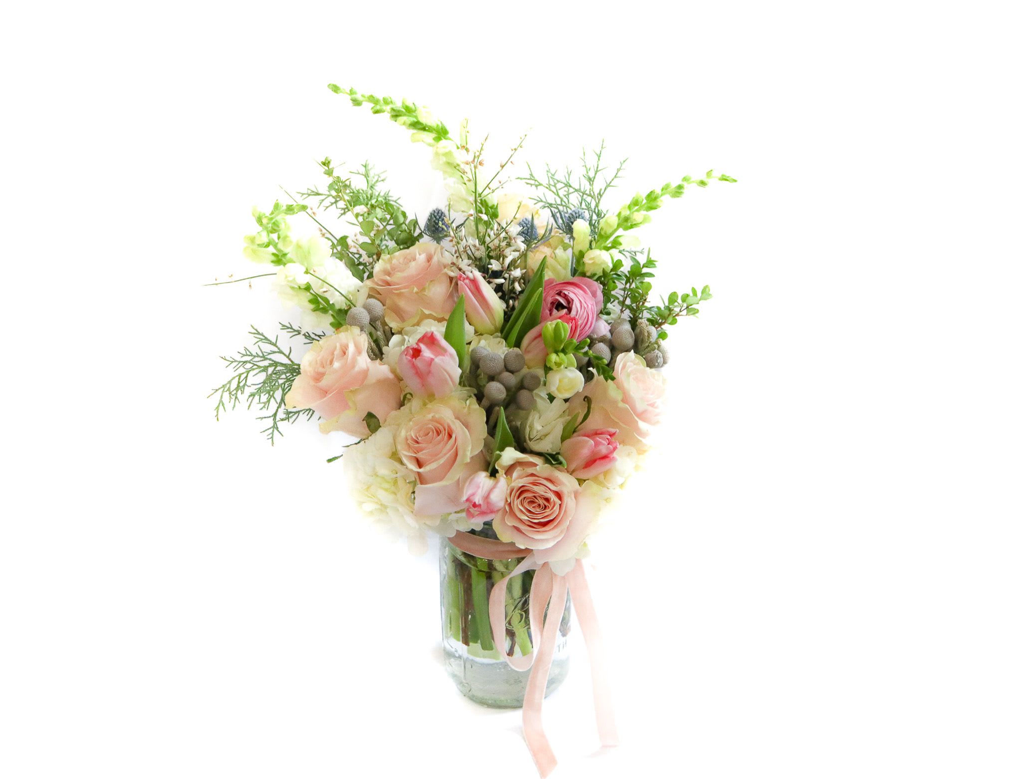 Pink and cream rose bouquet in a glass vase with a ribbon