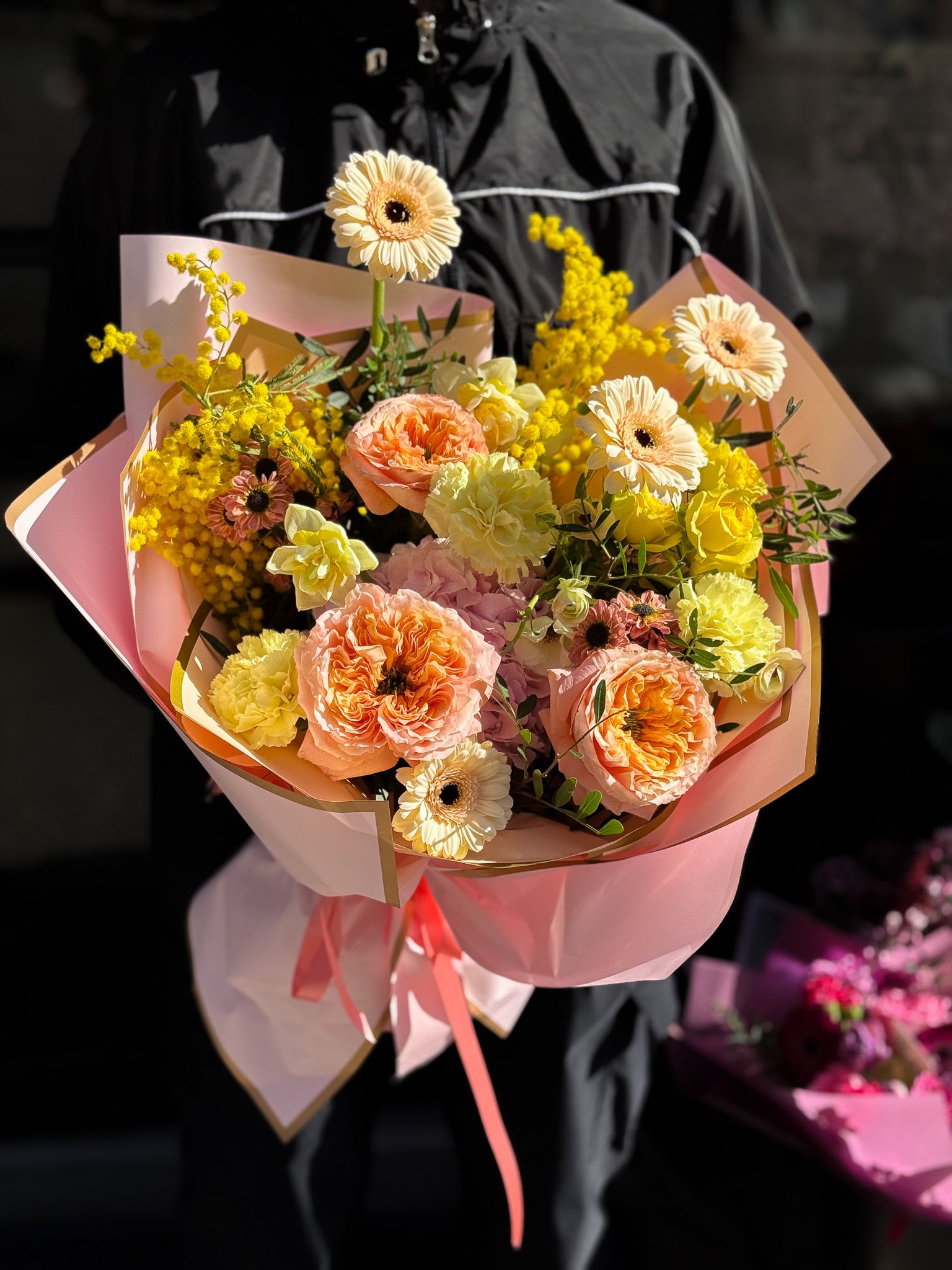 Pink and yellow bouquet with gerbera daisies and carnations wrapped in pastel paper