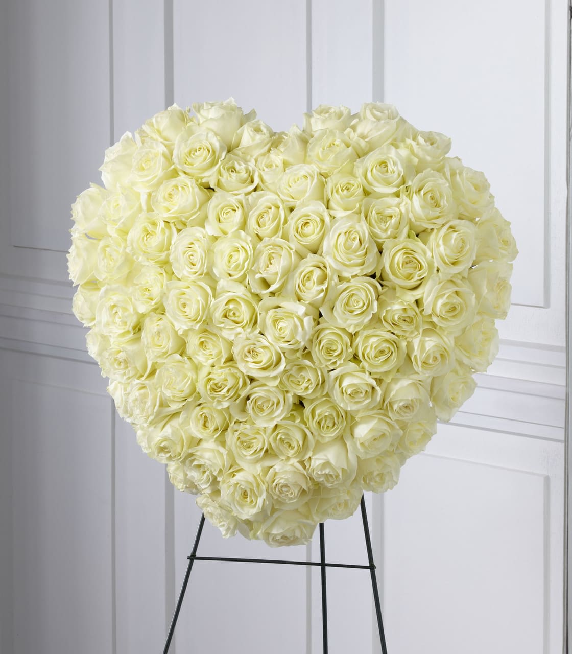 Heart-shaped arrangement of ivory roses on a black metal easel stand