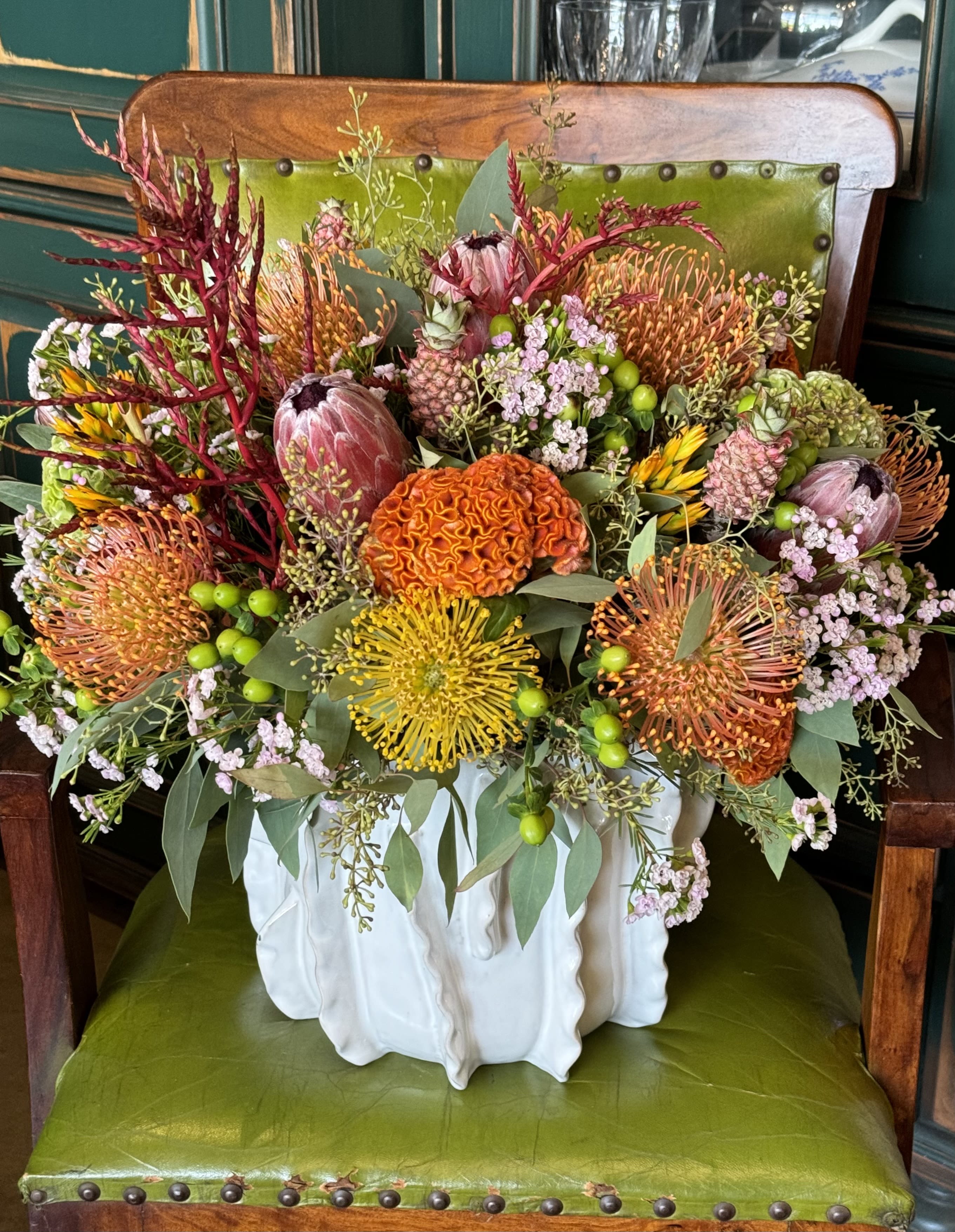 Mixed bouquet in a white ceramic vase with orange, yellow, pink, and green blooms