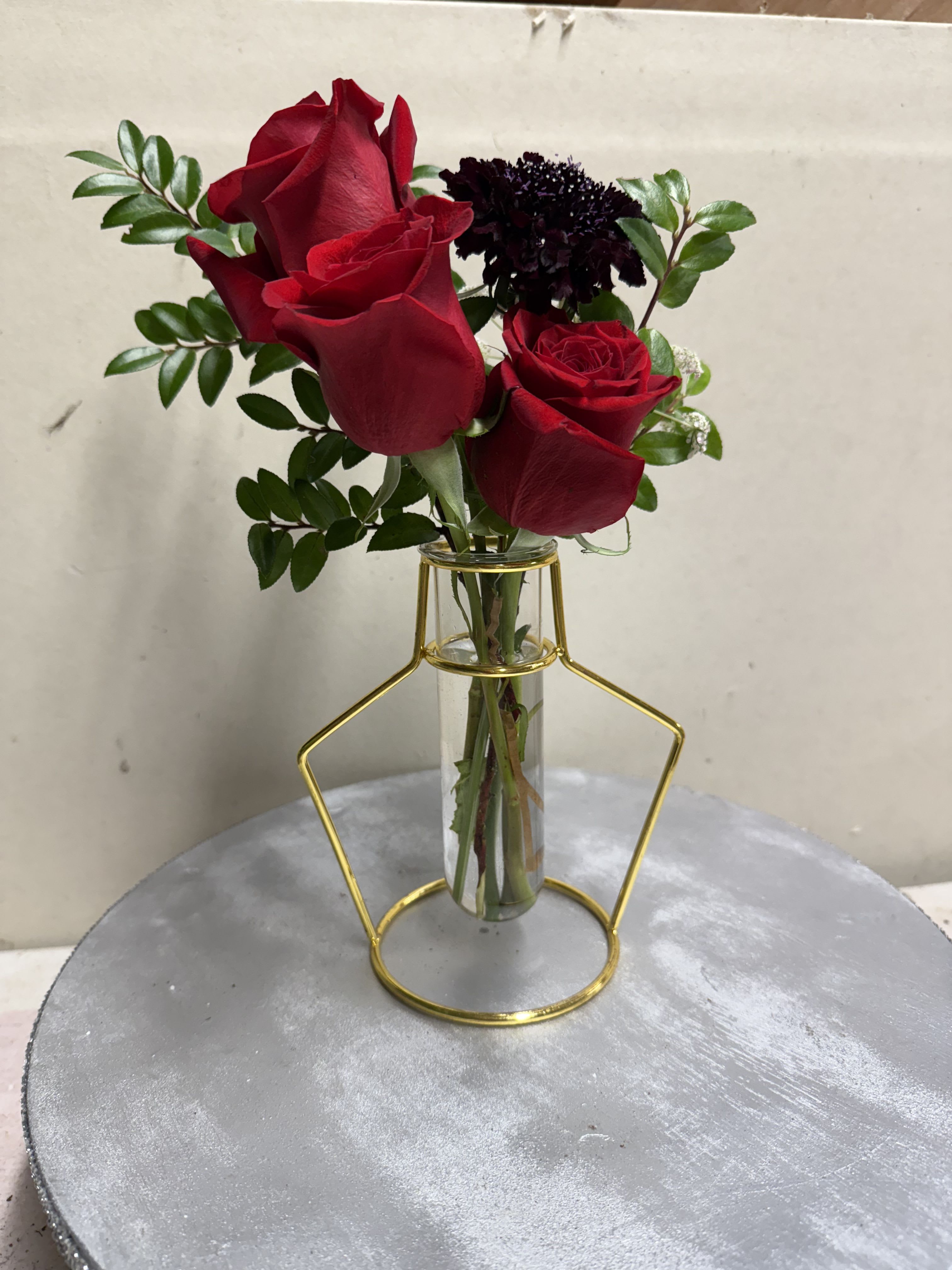 Red roses in a clear glass vase with greenery
