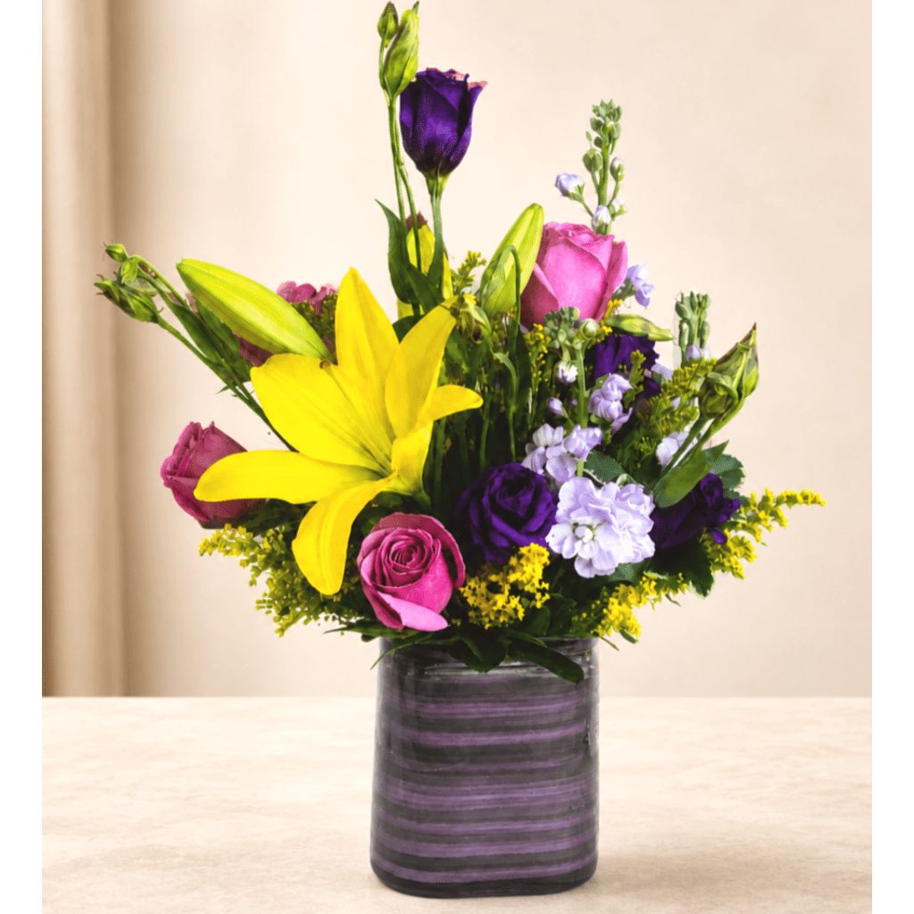 Colorful bouquet of lilies, roses, and purple blooms in a dark vase