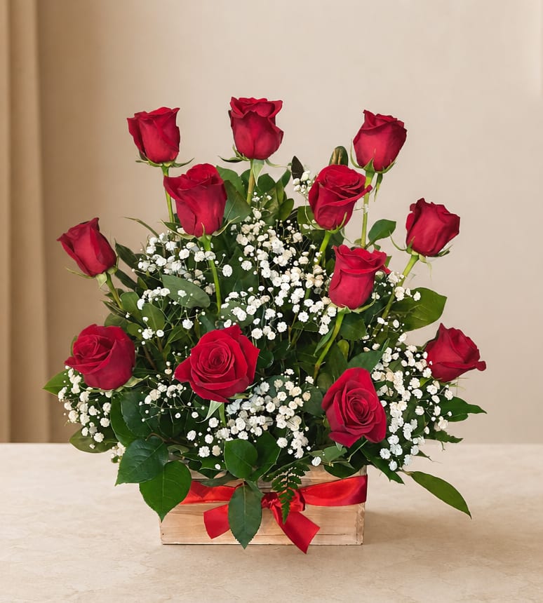 Red roses arranged in a wooden box with baby's breath and a red ribbon