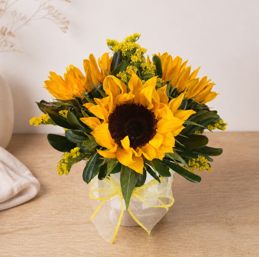 Sunflower arrangement in a small vase with a sheer yellow ribbon