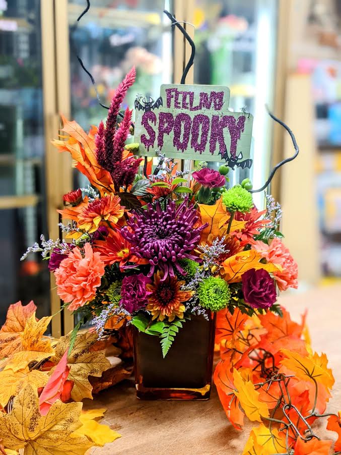 Halloween floral arrangement in a vase with a "Filling Spoon" sign