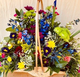 Large basket arrangement of multicolored flowers with a wooden handle
