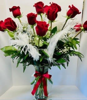 Bouquet of red roses in a clear glass vase with white feathers
