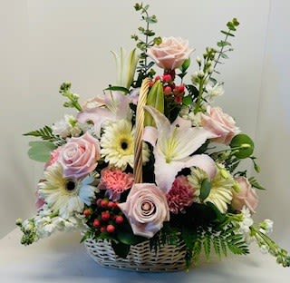 Basket arrangement of pink roses, lilies, and daisies
