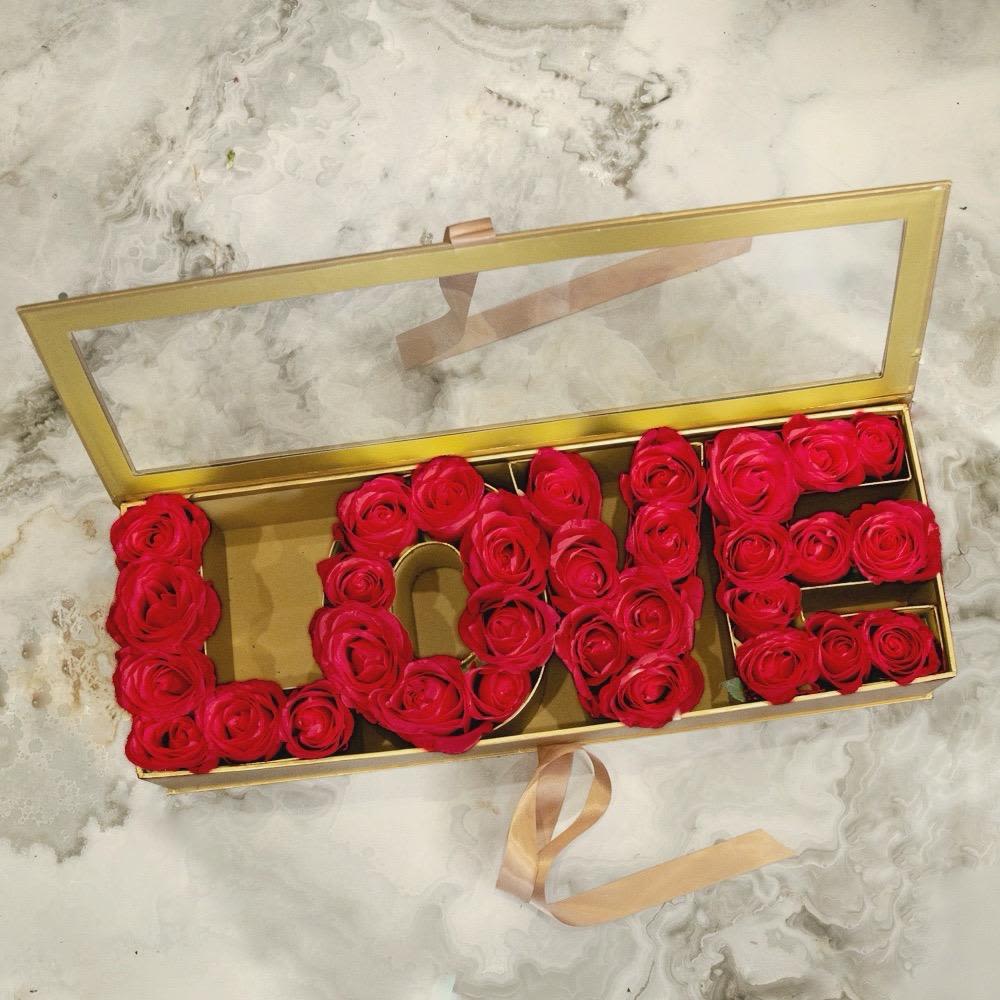 Red roses arranged in a gold box spelling "LOVE"