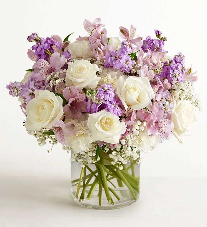 Bouquet of white roses and pink-purple flowers in a clear glass vase