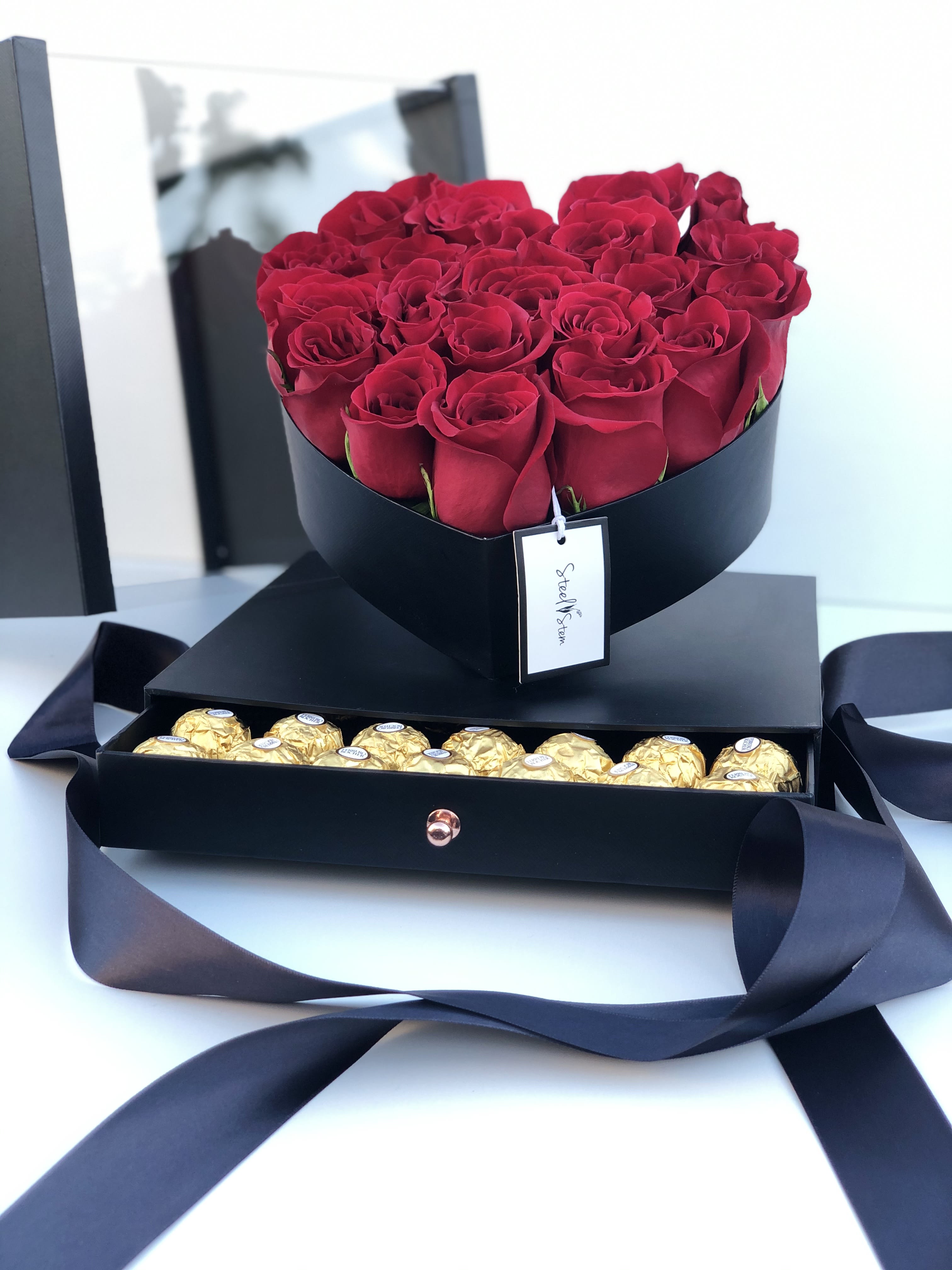 Red roses in a black box with gold chocolates in a drawer