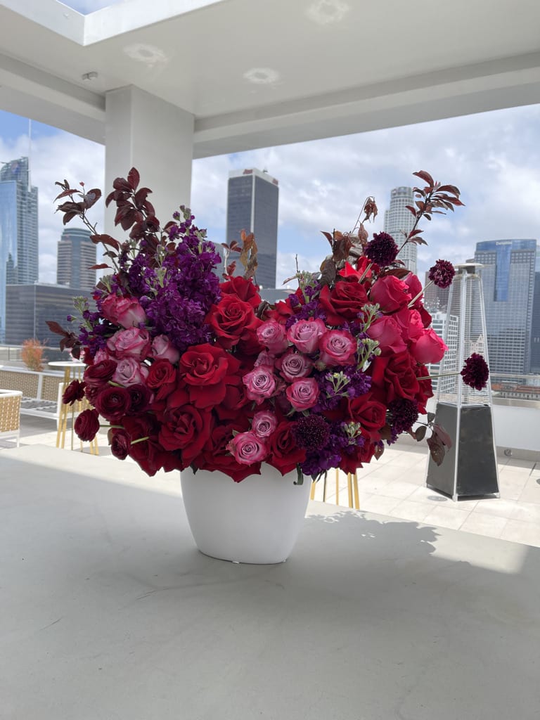Large arrangement of red and pink roses in a white vase