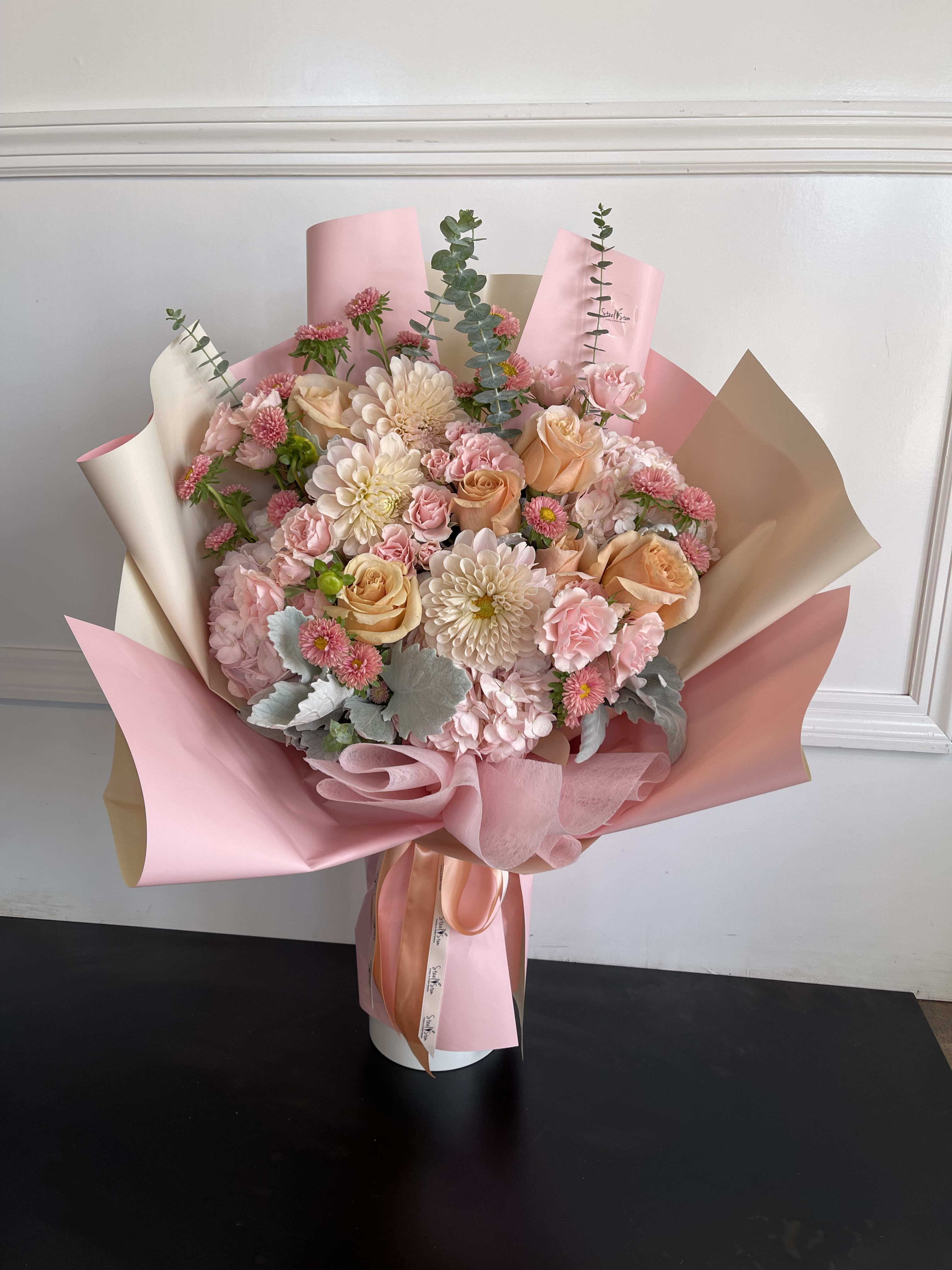 Pink and peach bouquet with roses, chrysanthemums, and carnations in pastel wrap
