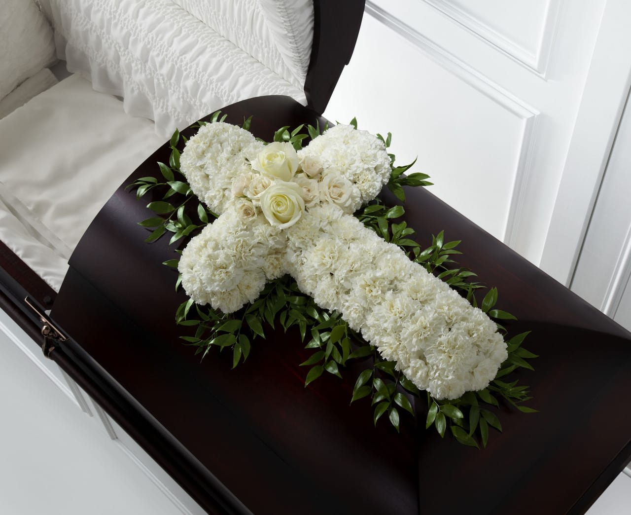 TLSP The Peaceful Memories Casket Spray - The Peaceful Memories Casket Spray is a gorgeous way to commemorate the faith and devotion of the deceased. White carnations are arranged in the shape of a cross accented in the middle with white roses and spray roses, and along the sides with lush greens, to create a lovely casket spray that brings peace and solace to those that attend their final farewell. Approximately 31"H x 22"W.  Your purchase includes a complimentary personalized gift message.