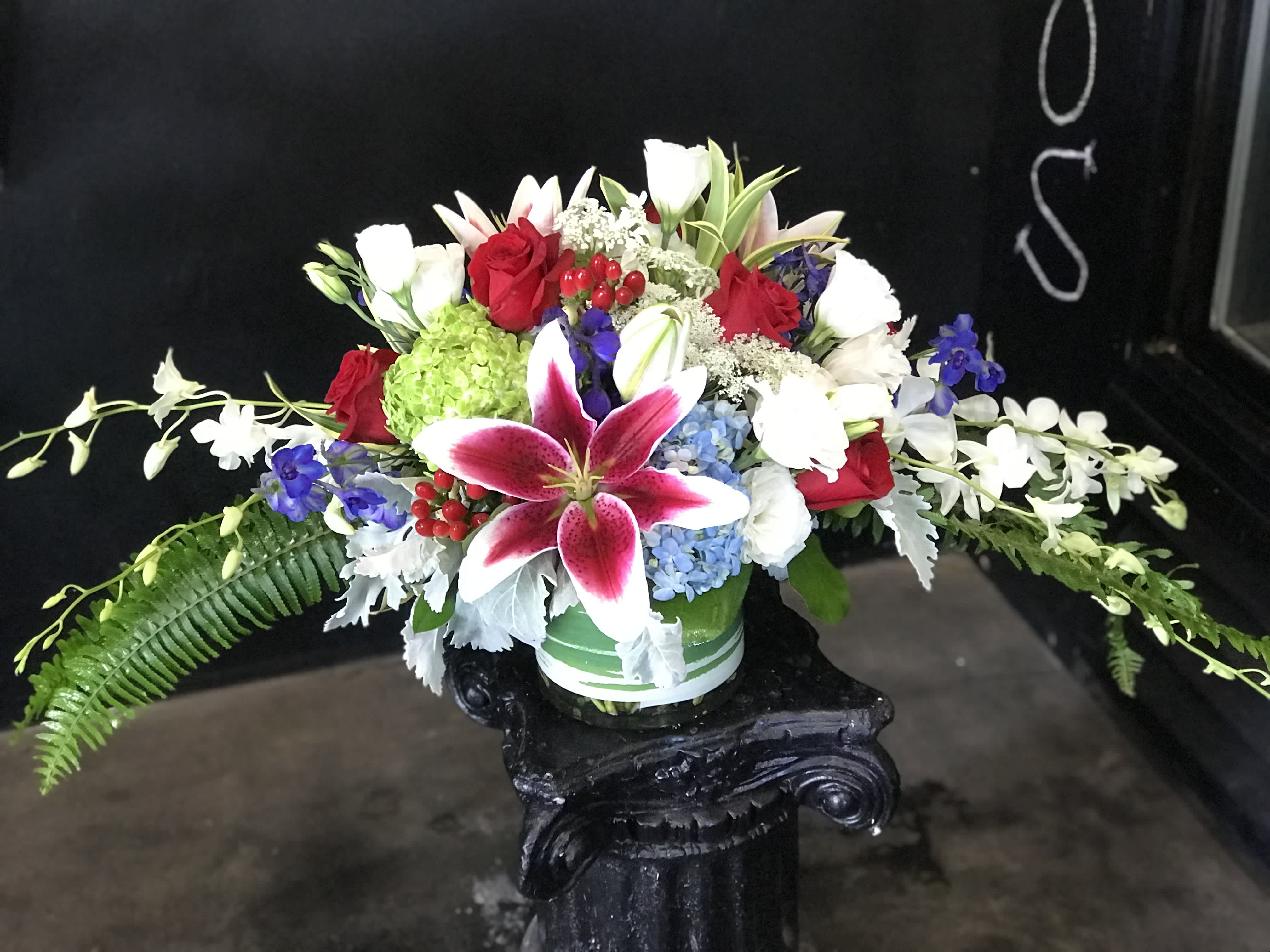 Mixed bouquet with red roses, white lilies, and a pink stargazer lily in a vase