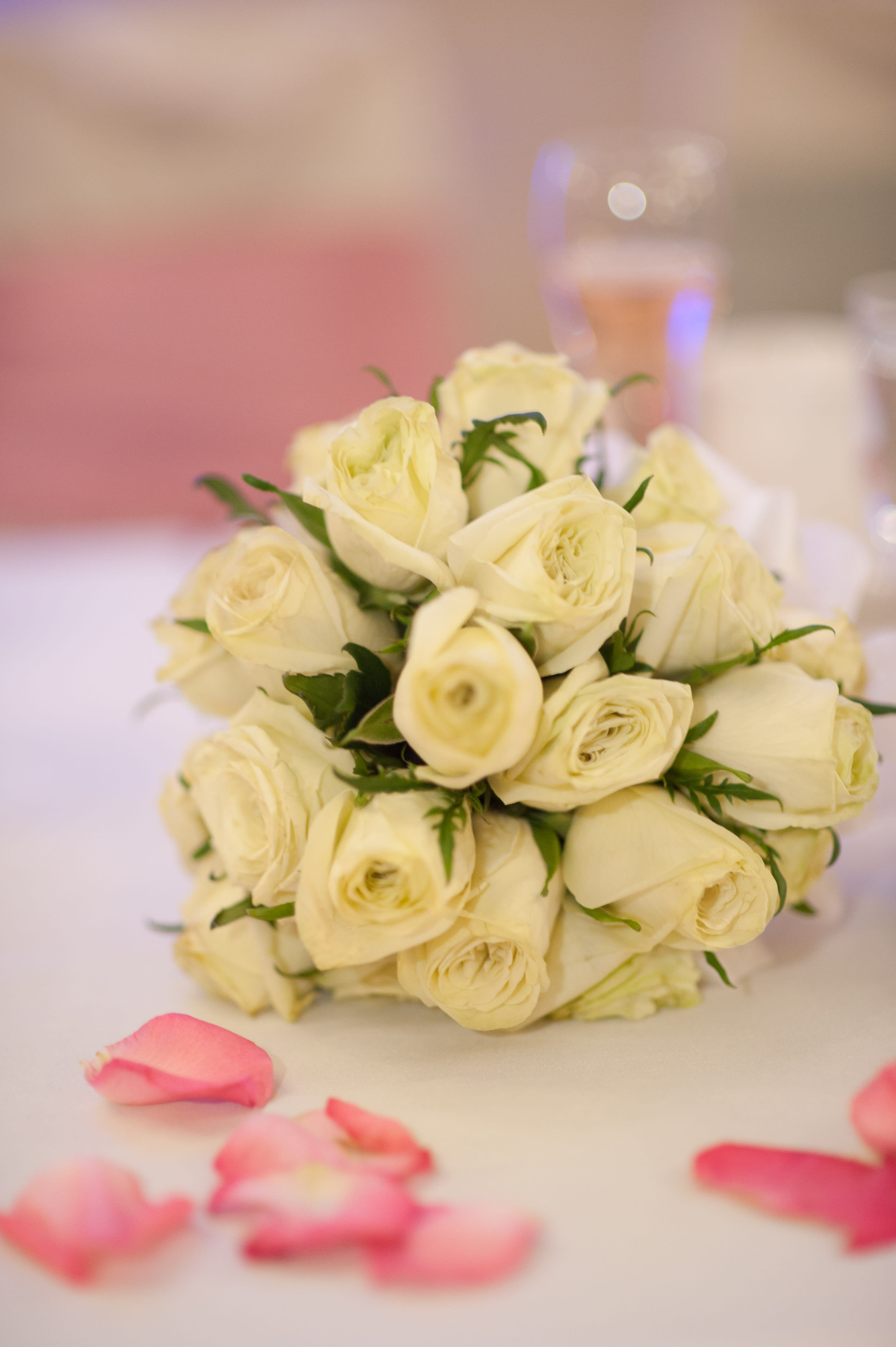 Bouquet of cream roses with pink petals scattered nearby