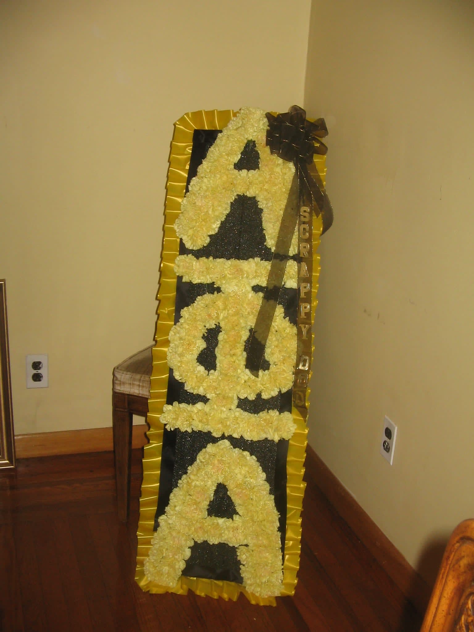 Tall floral standing tribute with yellow flowers spelling "SORRY"