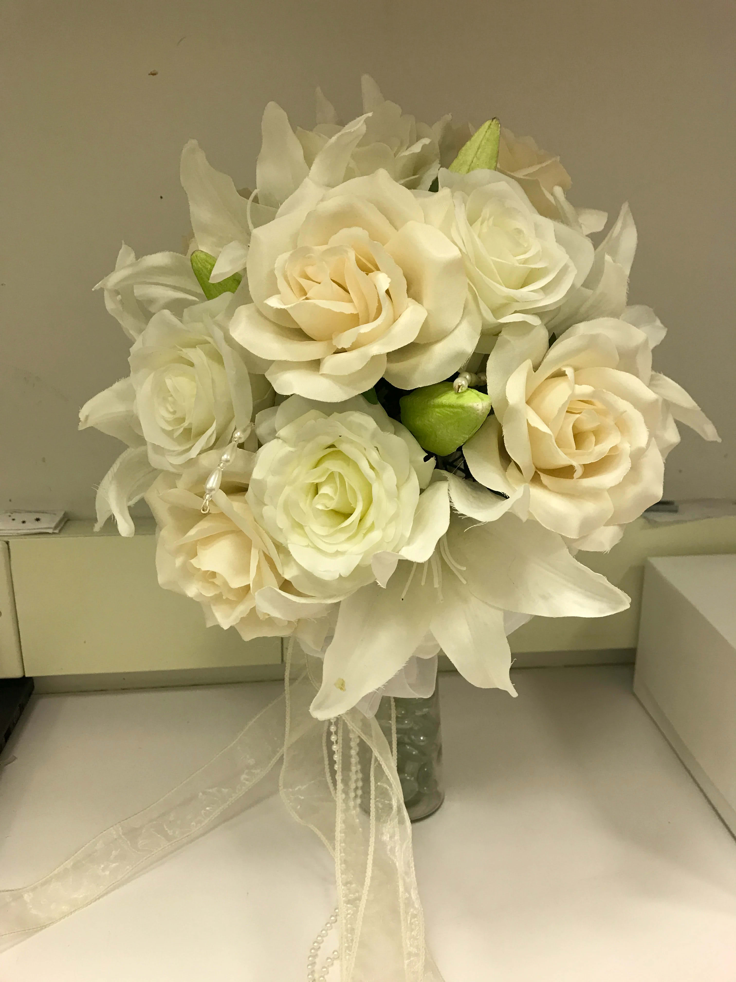 Cream rose bouquet with white lilies in a glass vase