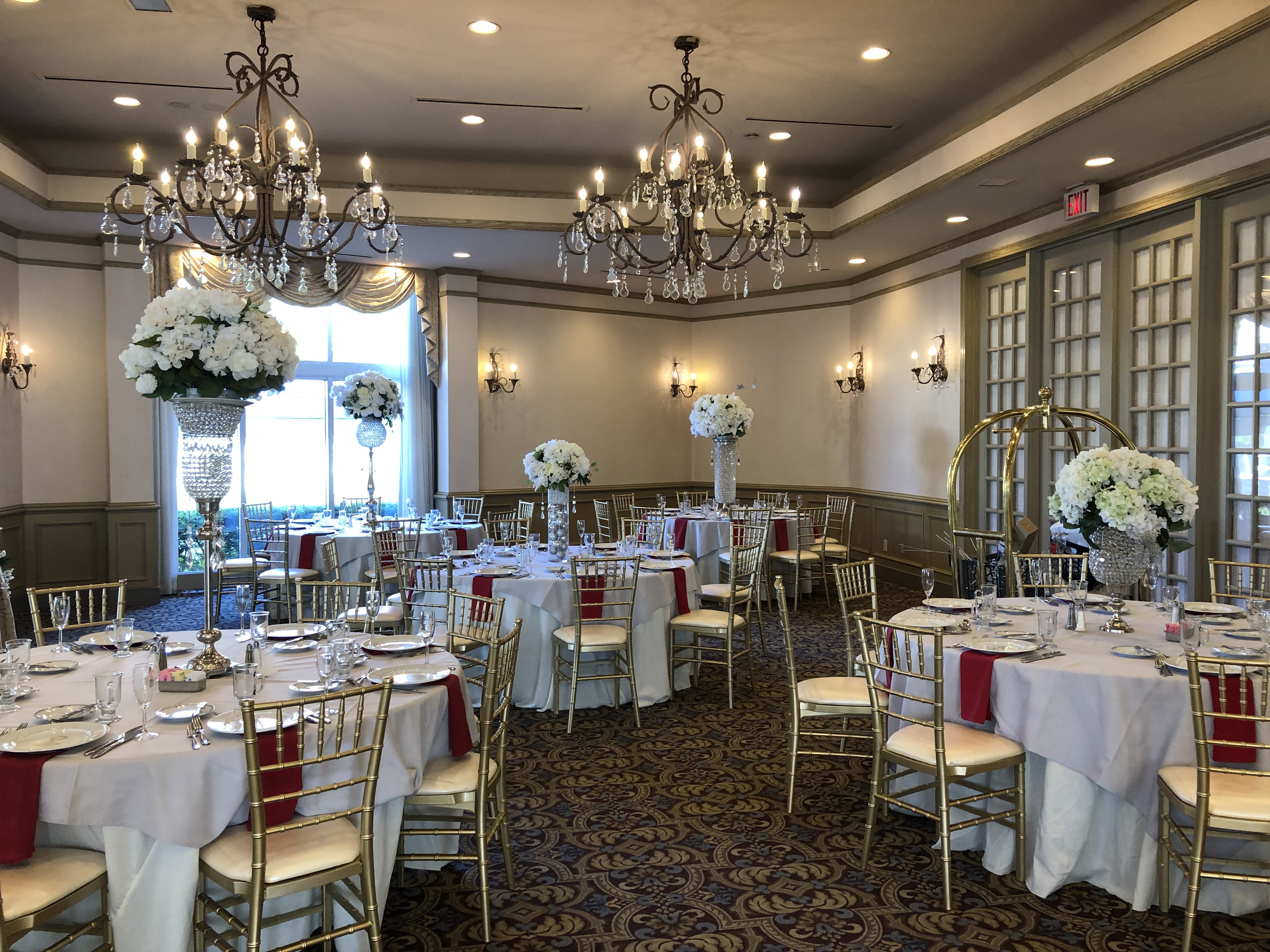 Banquet room with tall white floral centerpieces on round tables