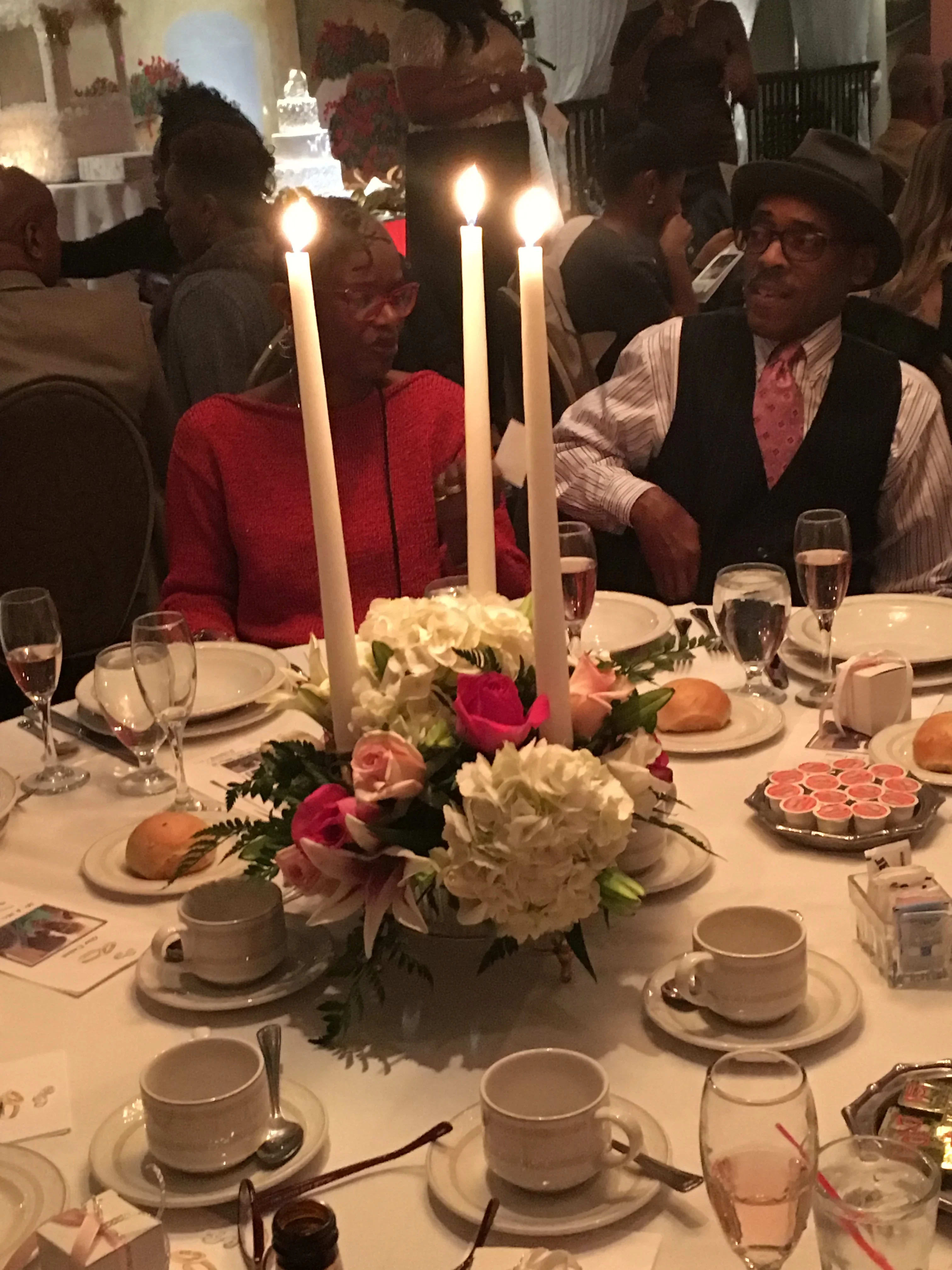 Candlelit table centerpiece with white and pink flowers at a formal dinner