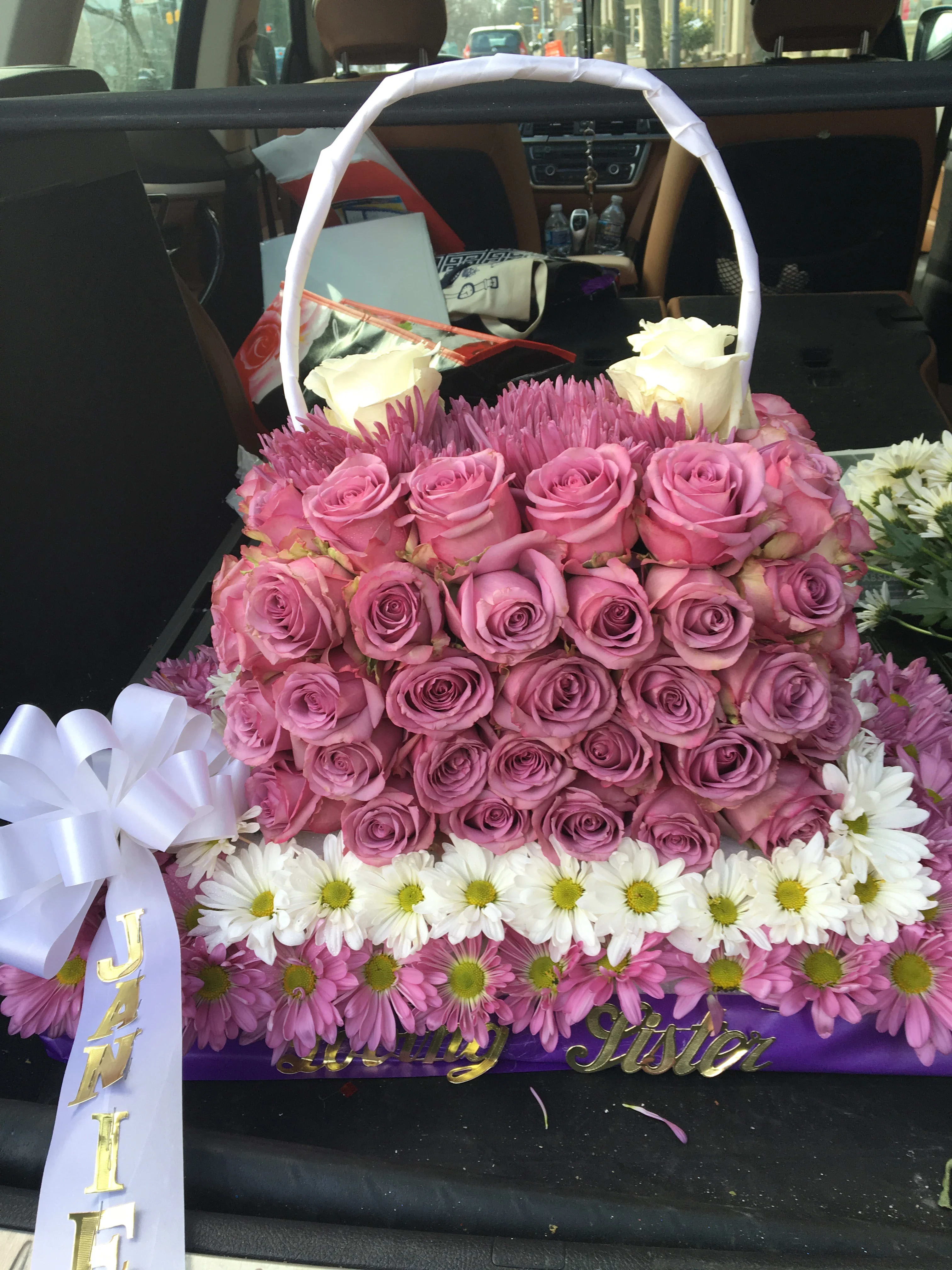 Basket arrangement of pink roses, white roses, and daisies