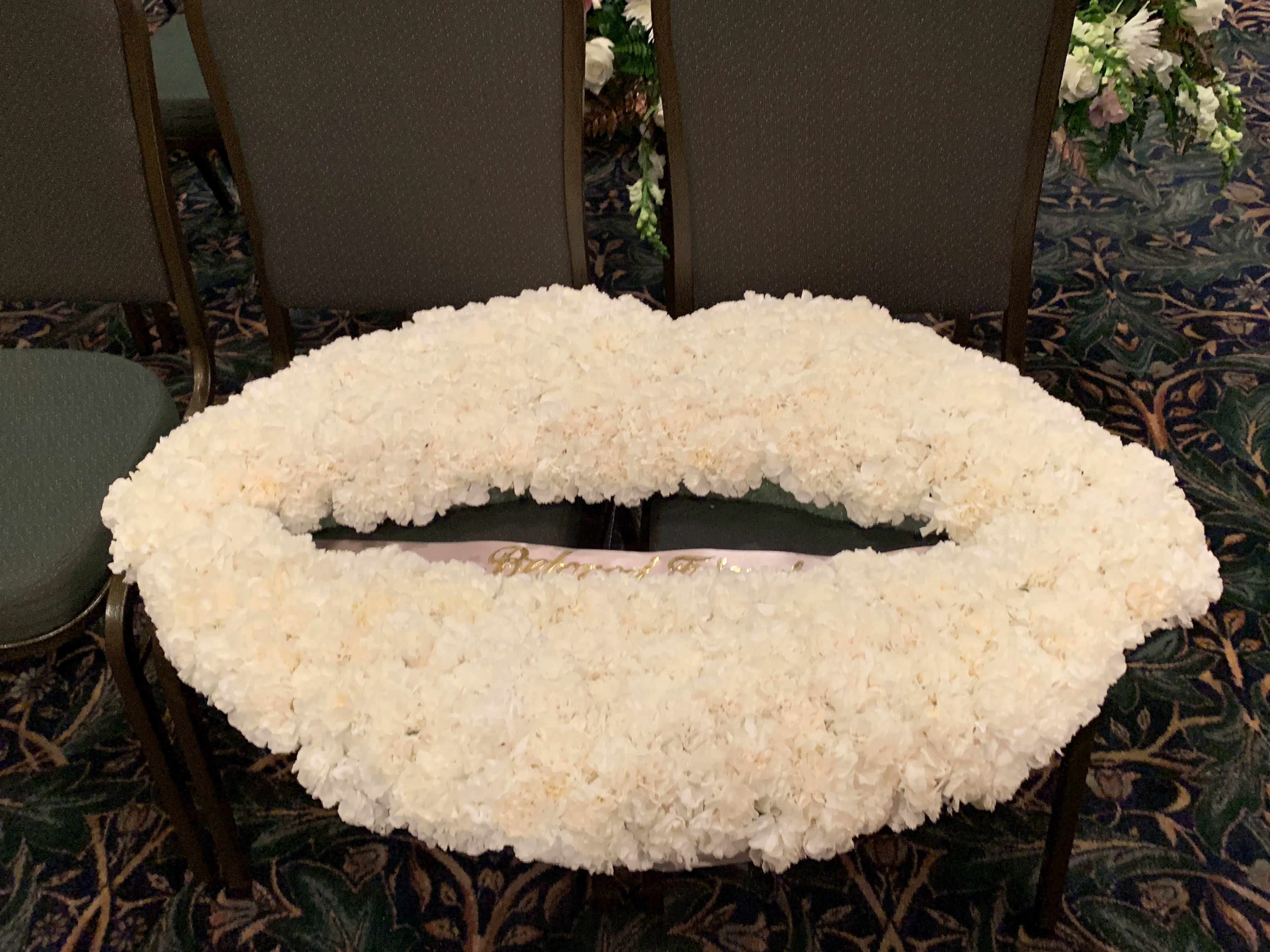 Large white floral wreath laid flat on chairs