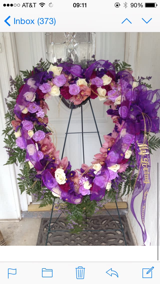 Purple floral wreath on a stand with roses and ribbon