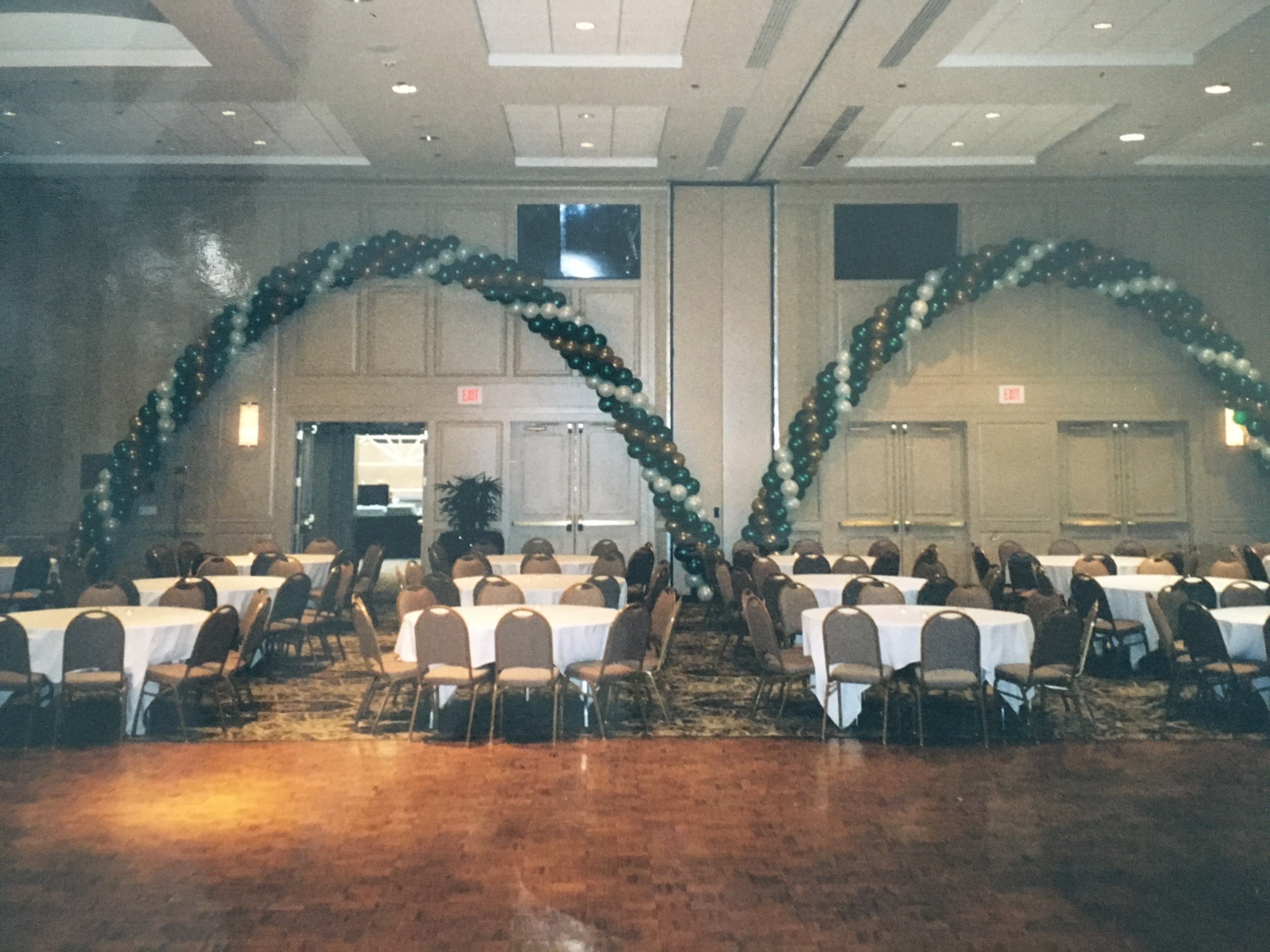 Balloon arches over round tables in a banquet hall