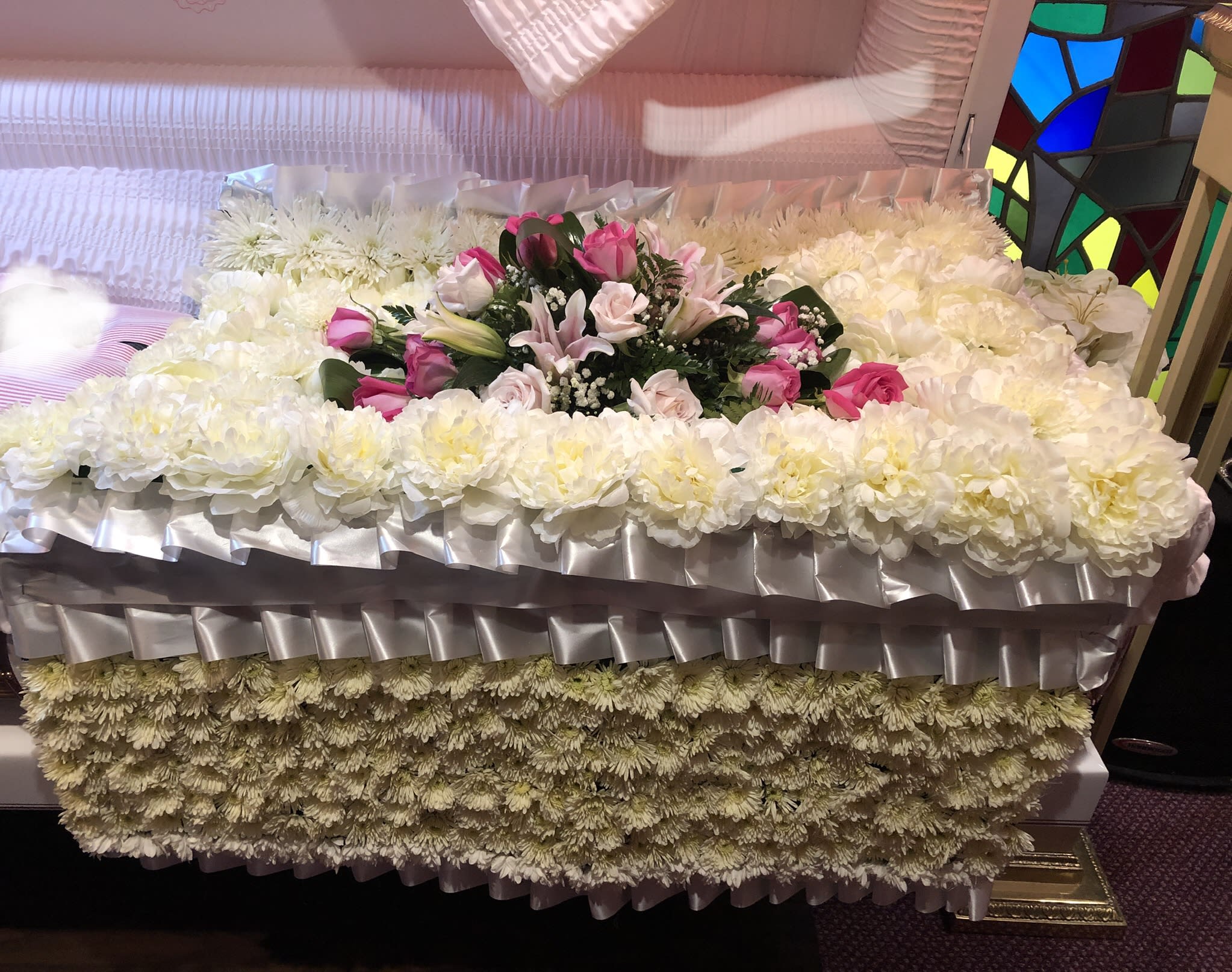 Large white floral casket spray with pink roses and lilies