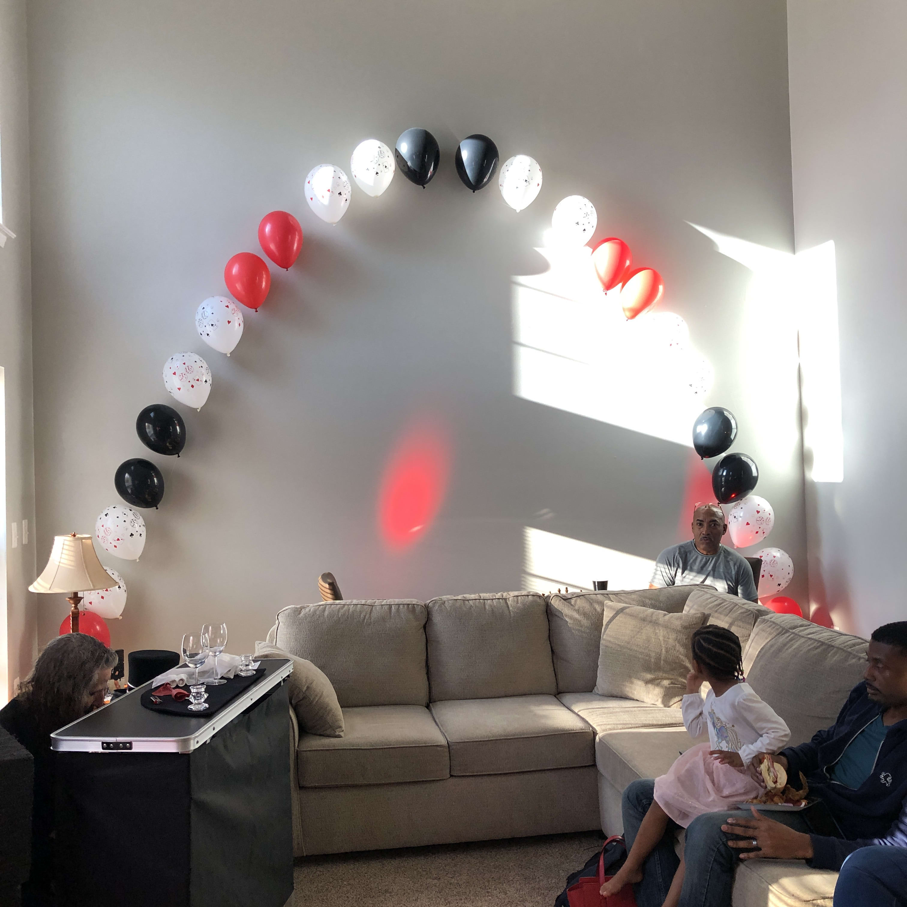 Balloon arch in red, white, and black over a living room sofa
