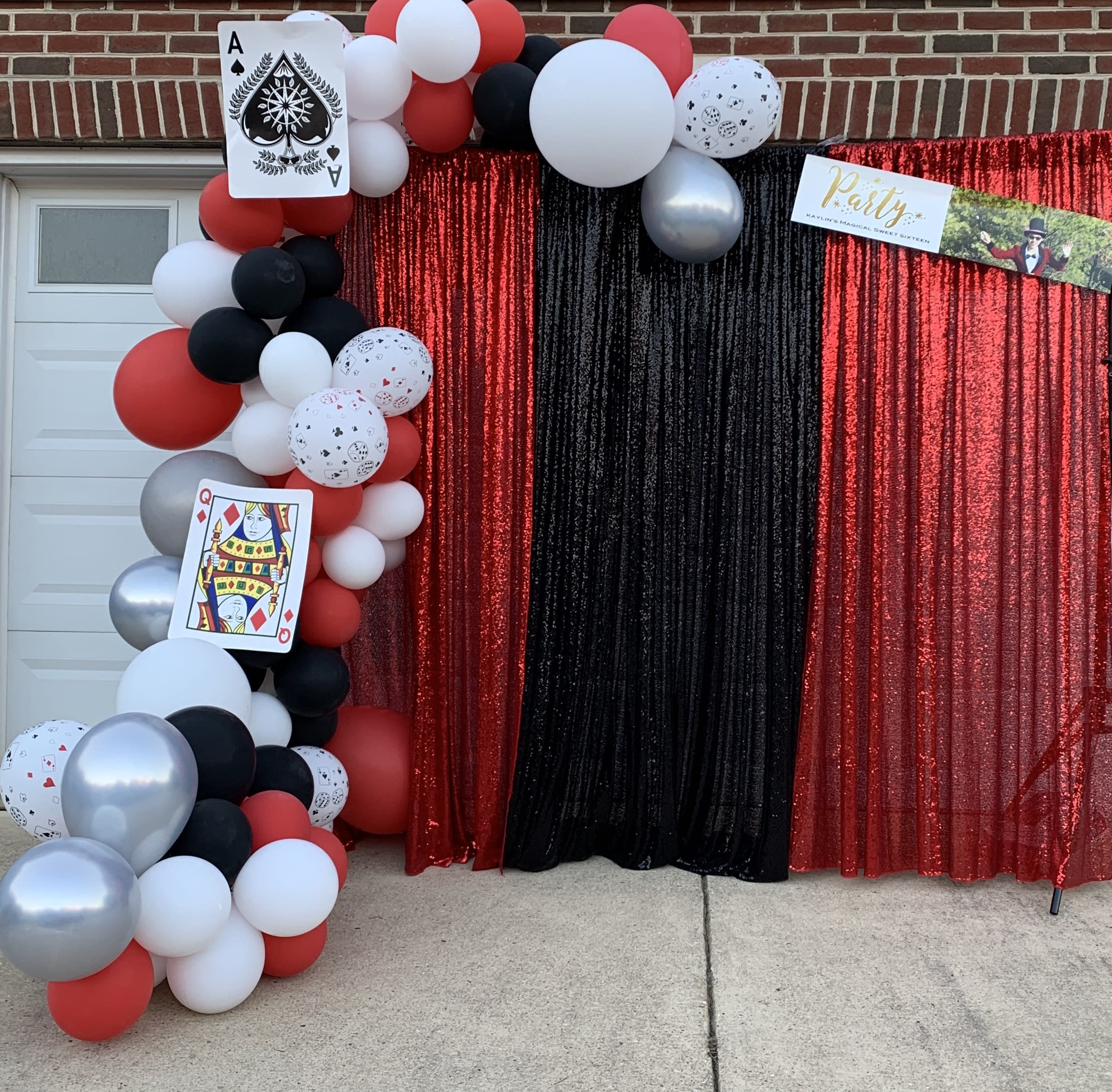 Red, black, white, and silver balloon arch with playing card decorations