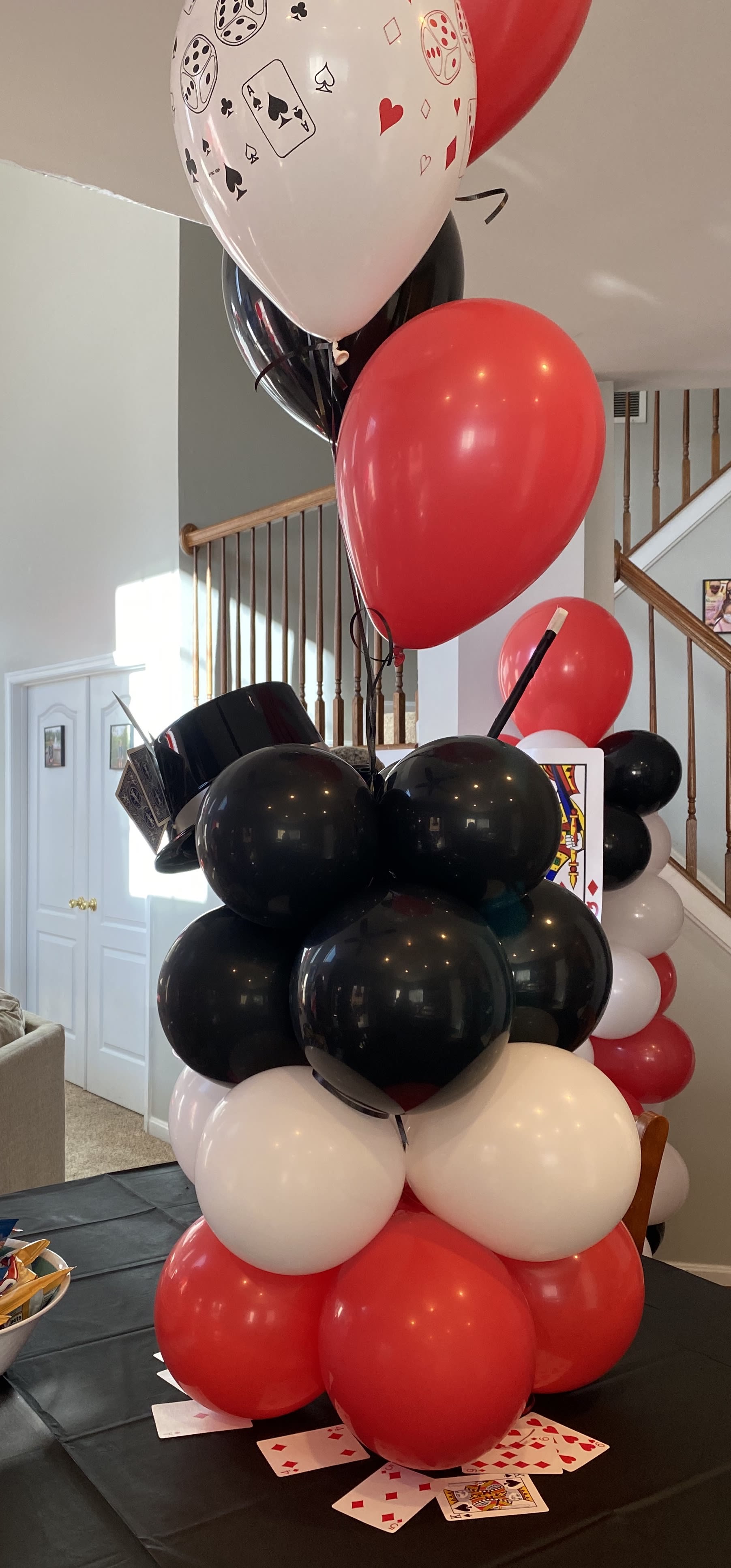 Cluster of red, black, white, and playing-card balloons on a table