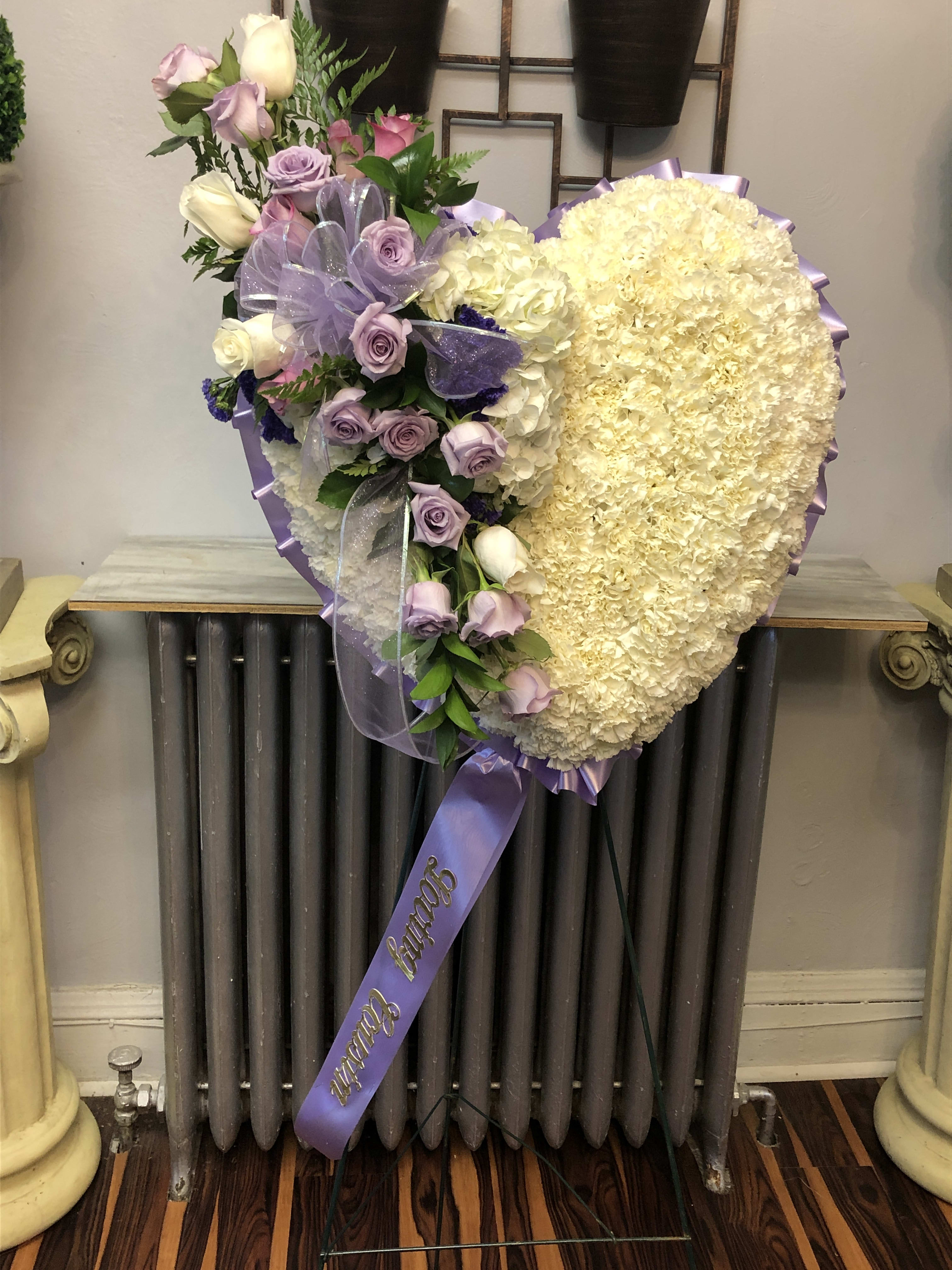 Heart-shaped floral spray with lavender roses and cream blooms on a stand