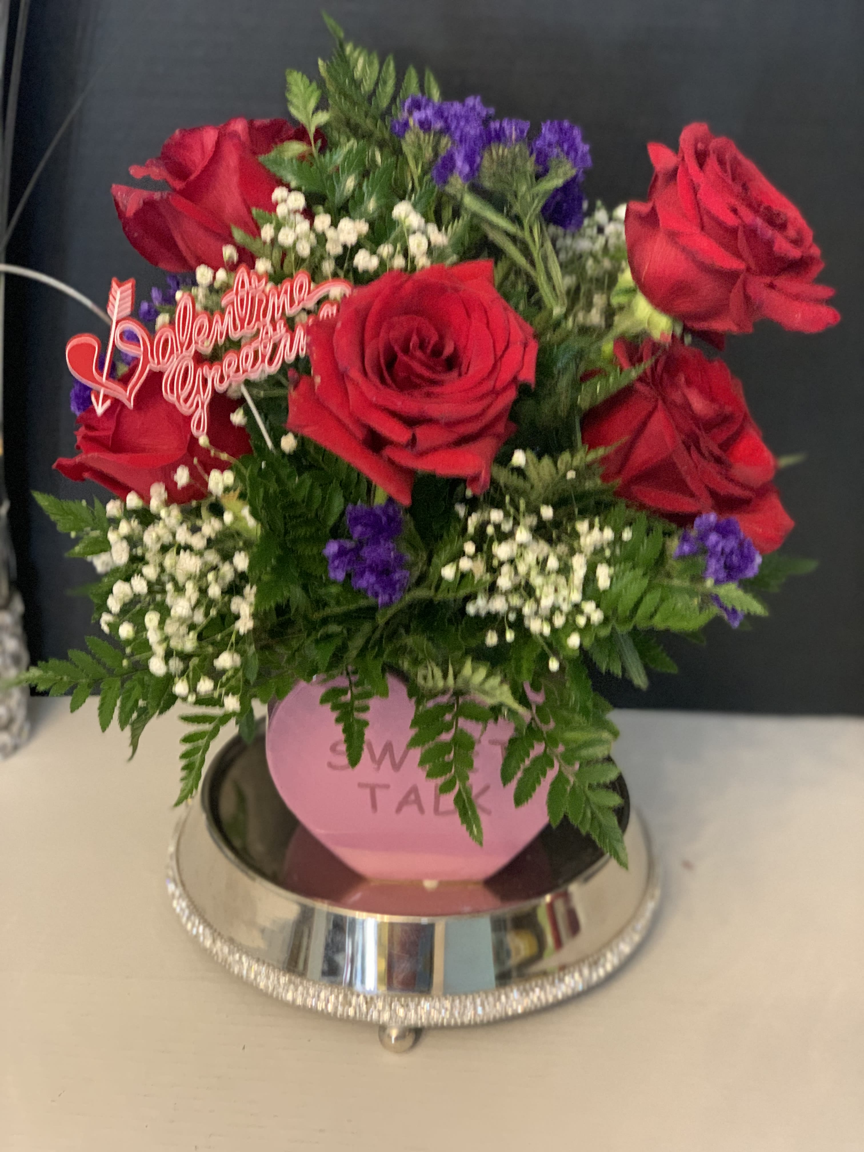Red roses with purple filler flowers in a pink vase