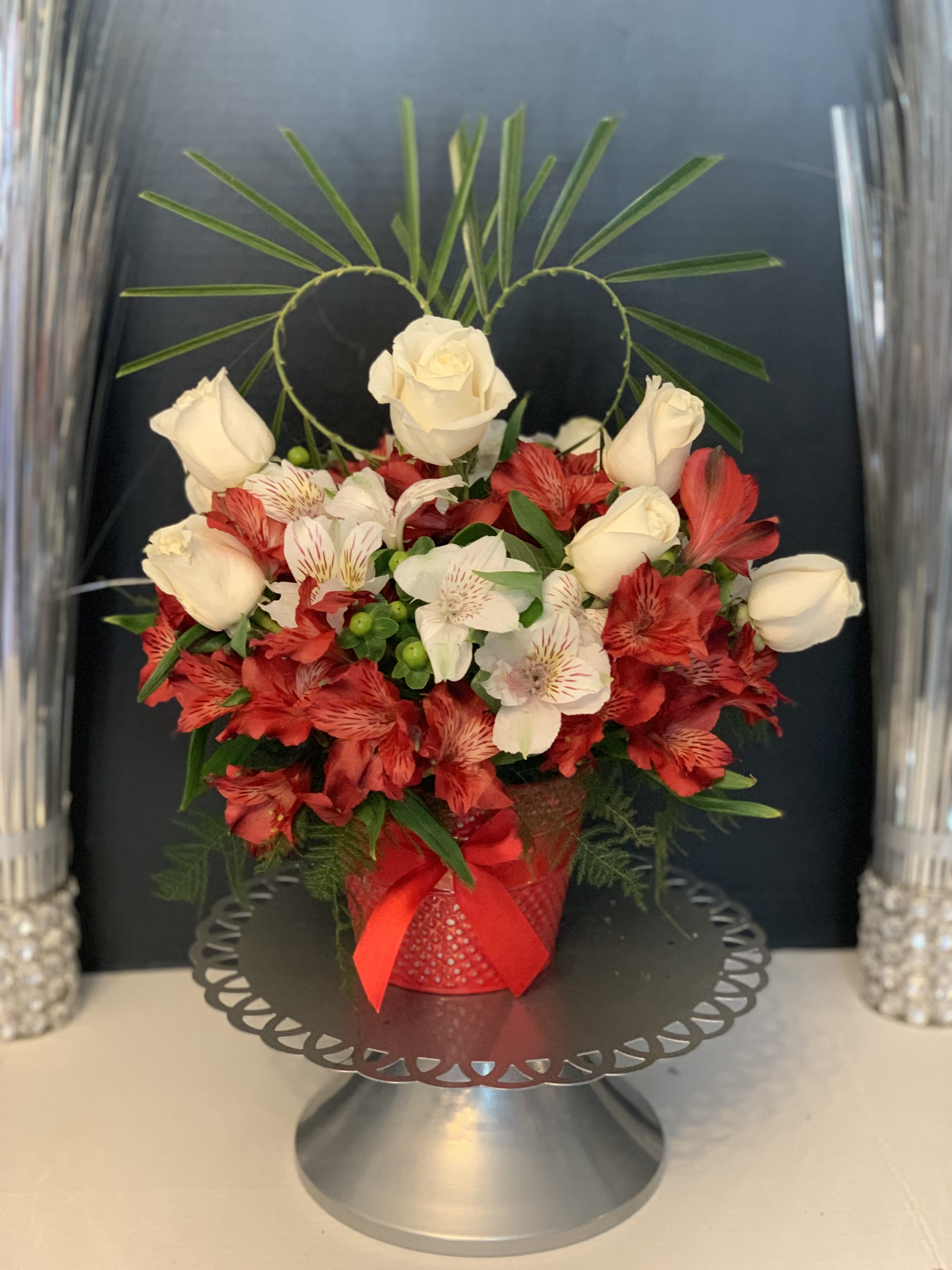 Red and white floral arrangement in a red vase with a ribbon