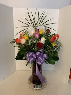 Mixed bouquet of roses with a purple ribbon in a vase