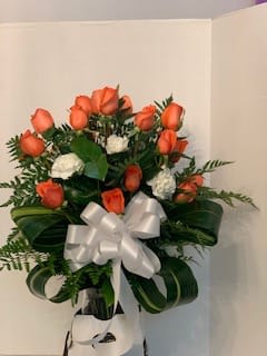 Orange rose bouquet with white flowers and a white ribbon