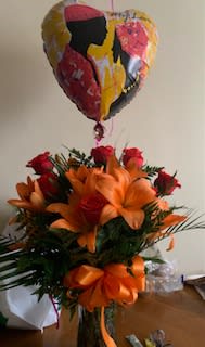 Bouquet of orange lilies and red roses with a heart-shaped balloon above