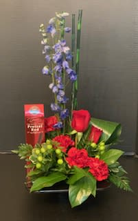 Red roses and blue flowers arranged in a low basket with a tall accent stem